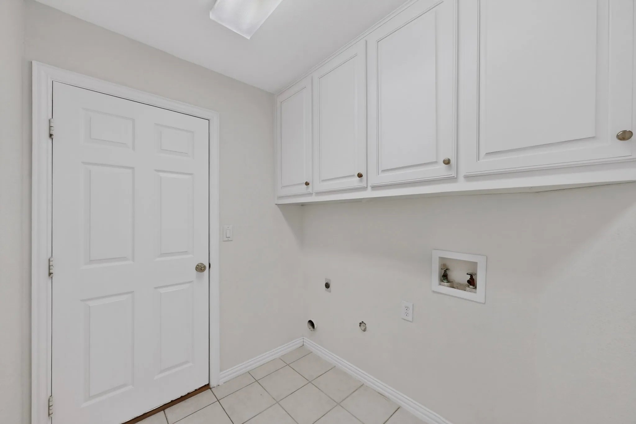 White panel door, white wall-mounted cabinetry, tile flooring, and light wall finishes