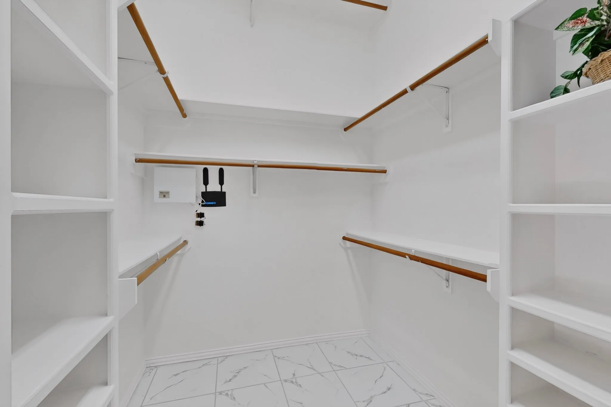 White built-in shelving, multiple hanging rods, and patterned tile flooring