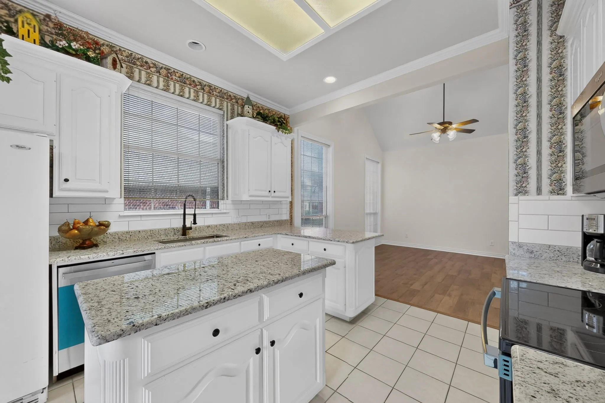 Kitchen featuring white cabinetry, light-toned countertops, a white subway tile backsplash, and tile flooring