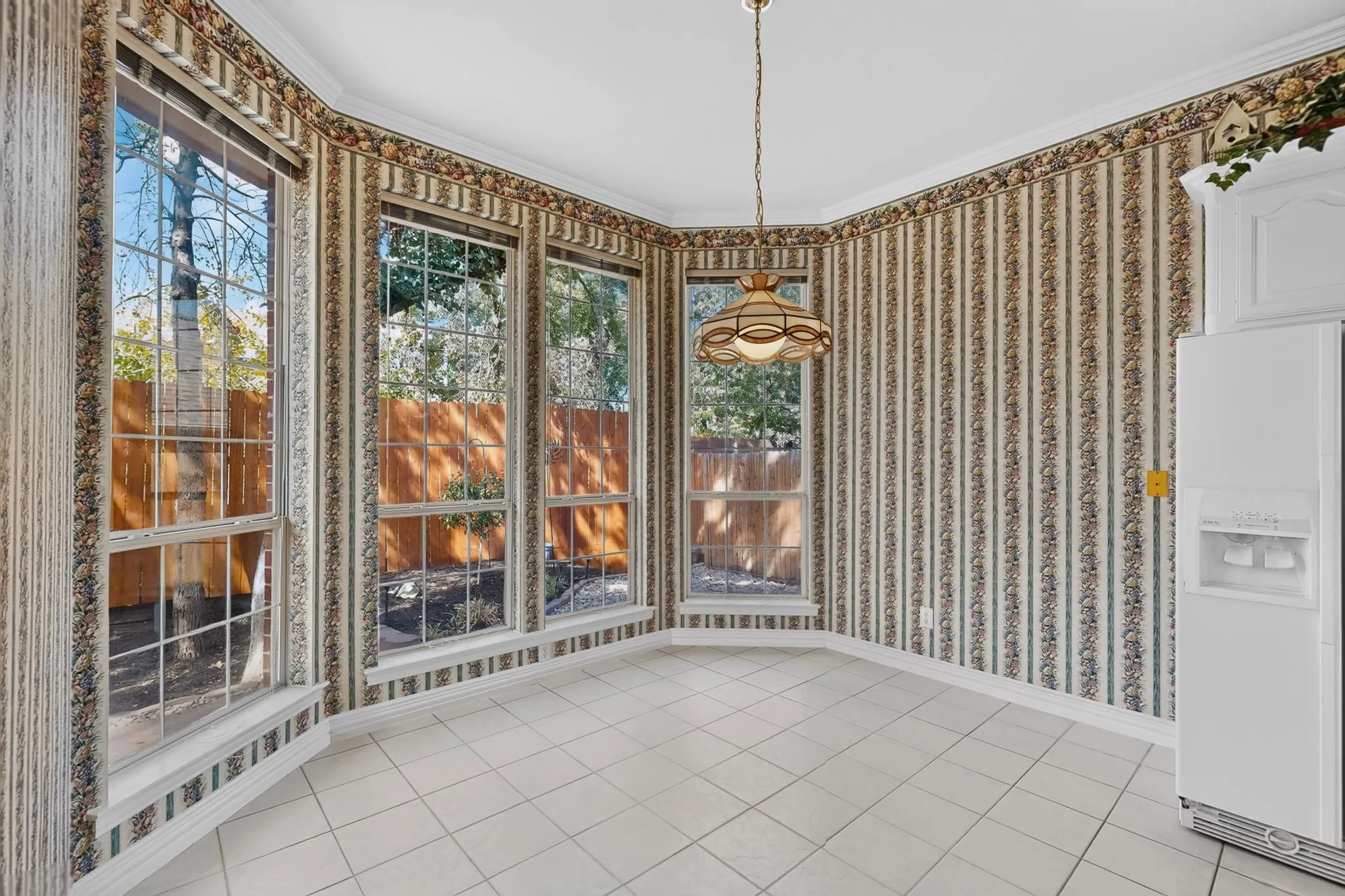 Bay window with multiple pane windows, tile flooring, crown molding, and a decorative pendant light fixture