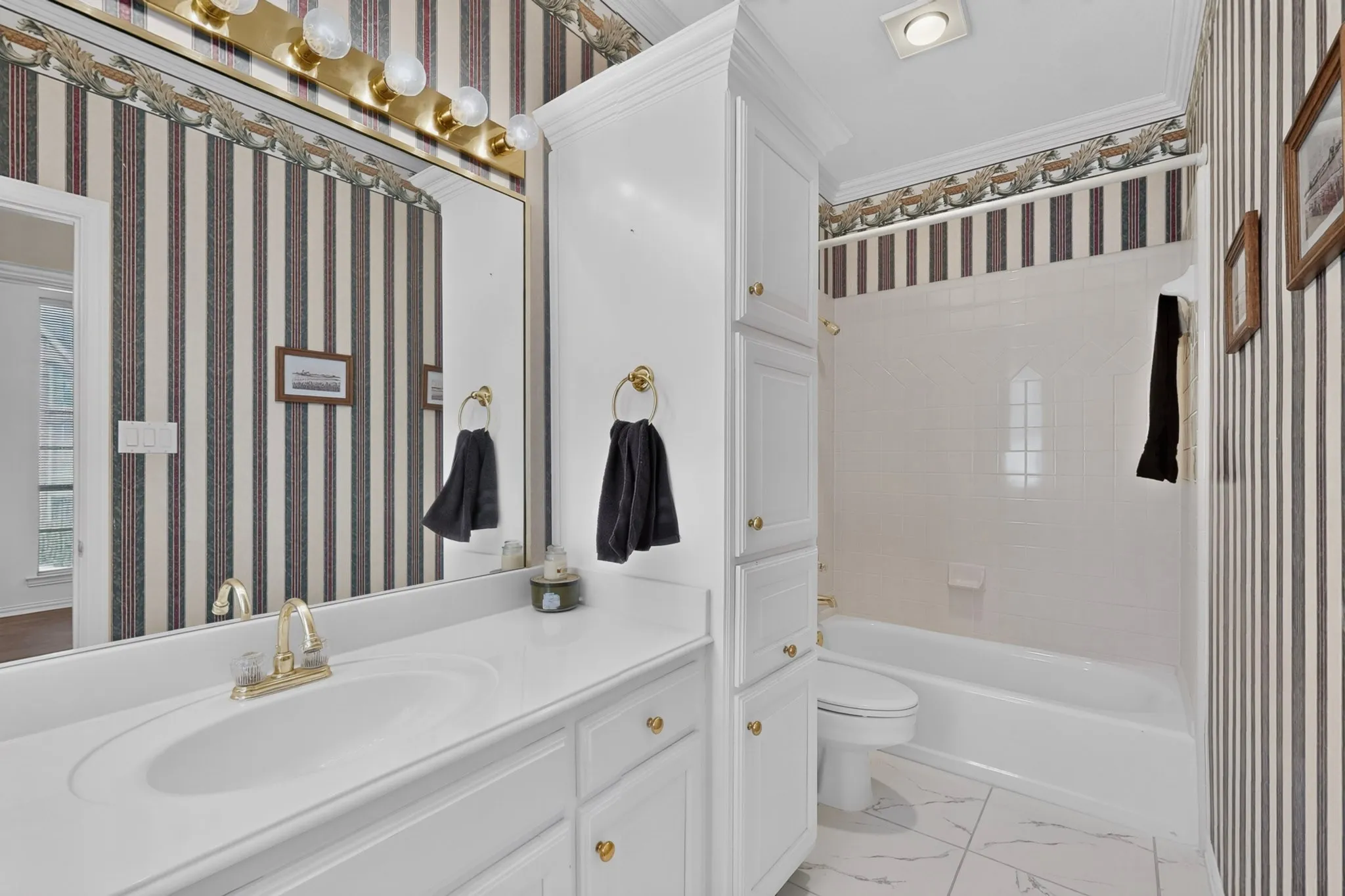 Vanity with integrated sink, gold-finish faucet, and overhead lighting fixture