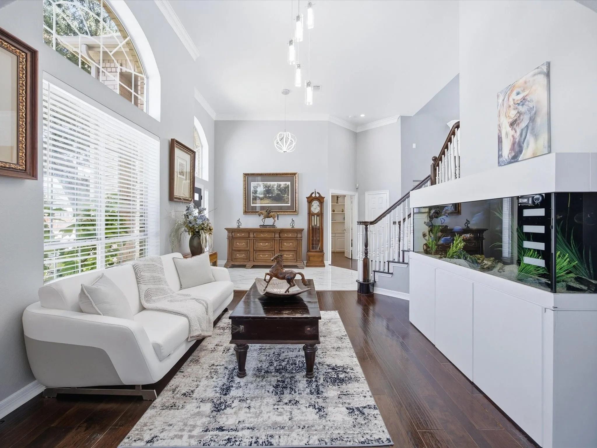 Grand entry with high ceilings, wood-finish flooring, a built-in aquarium, and an elegant staircase with white risers and dark wood handrails