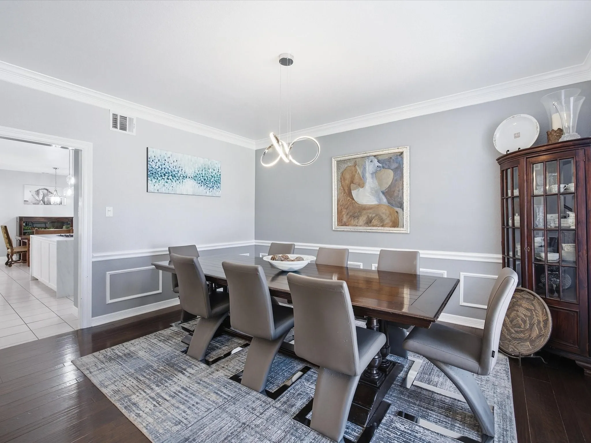 Hardwood flooring, crown molding, chair rail molding, and a modern chandelier