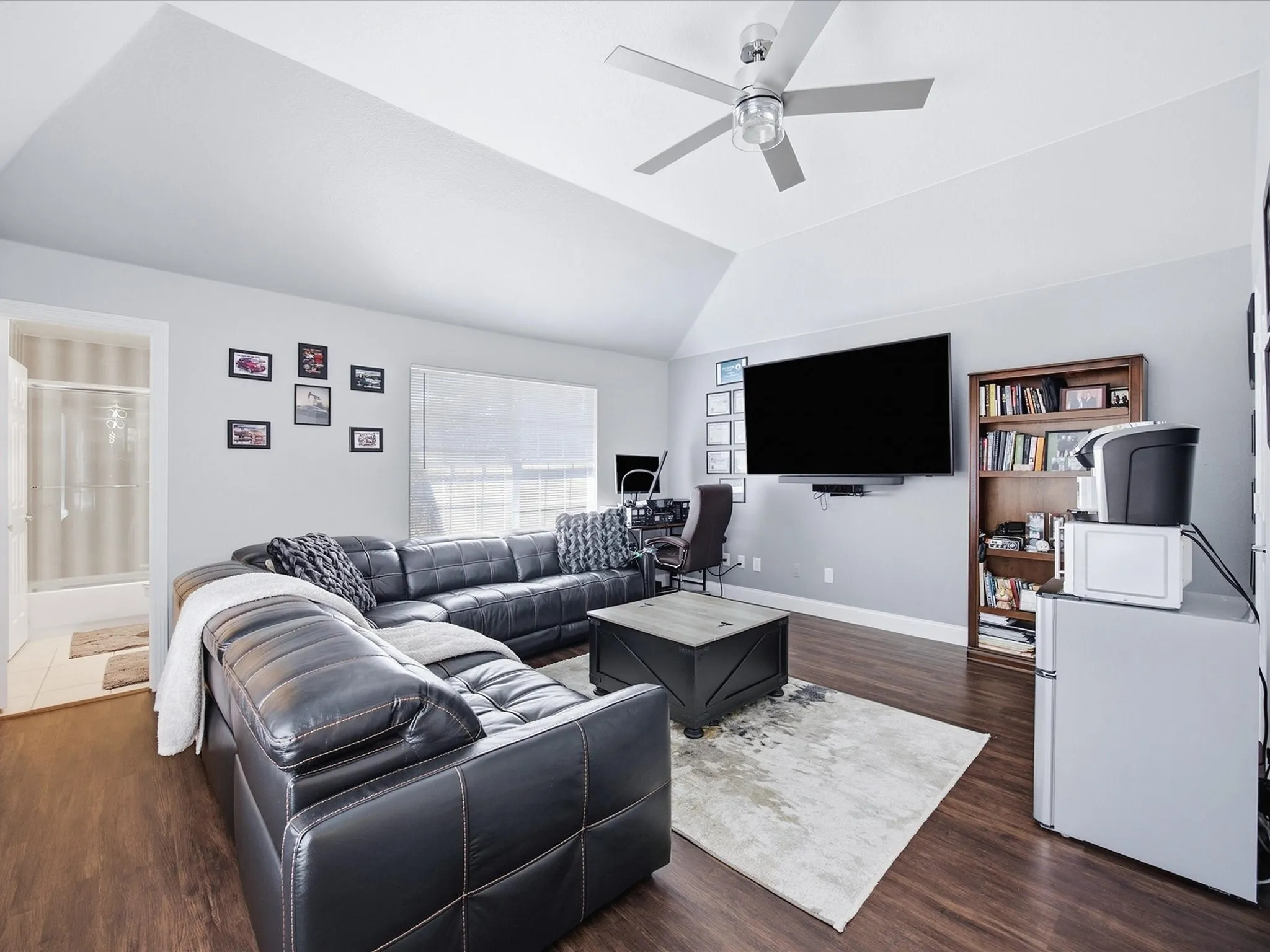 Vaulted ceiling with a ceiling fan, recessed window, wood-finish flooring, and a built-in shower with clear glass door