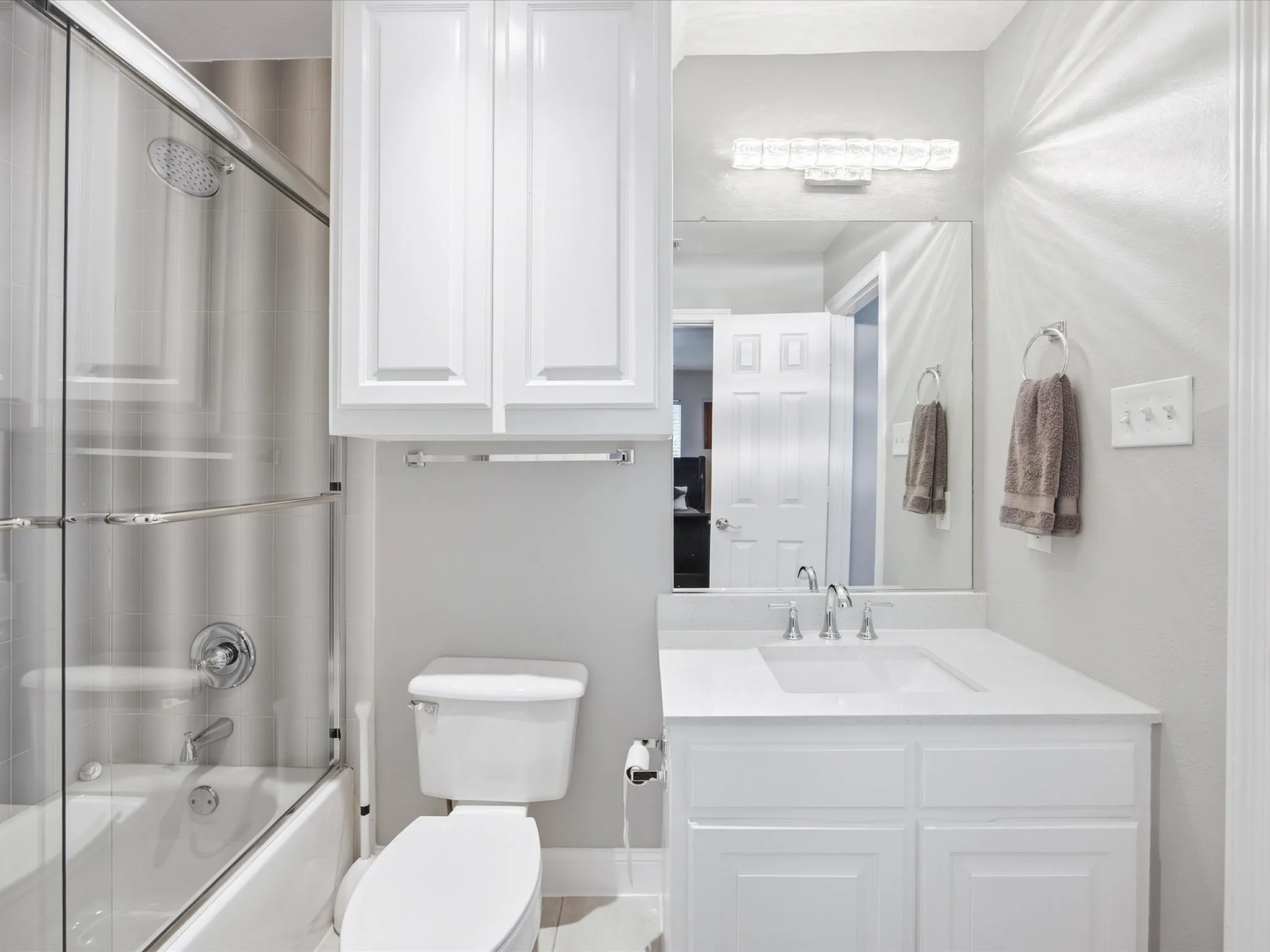 White shaker vanity with integrated sink and chrome faucet, full-width mirror, and overhead lighting