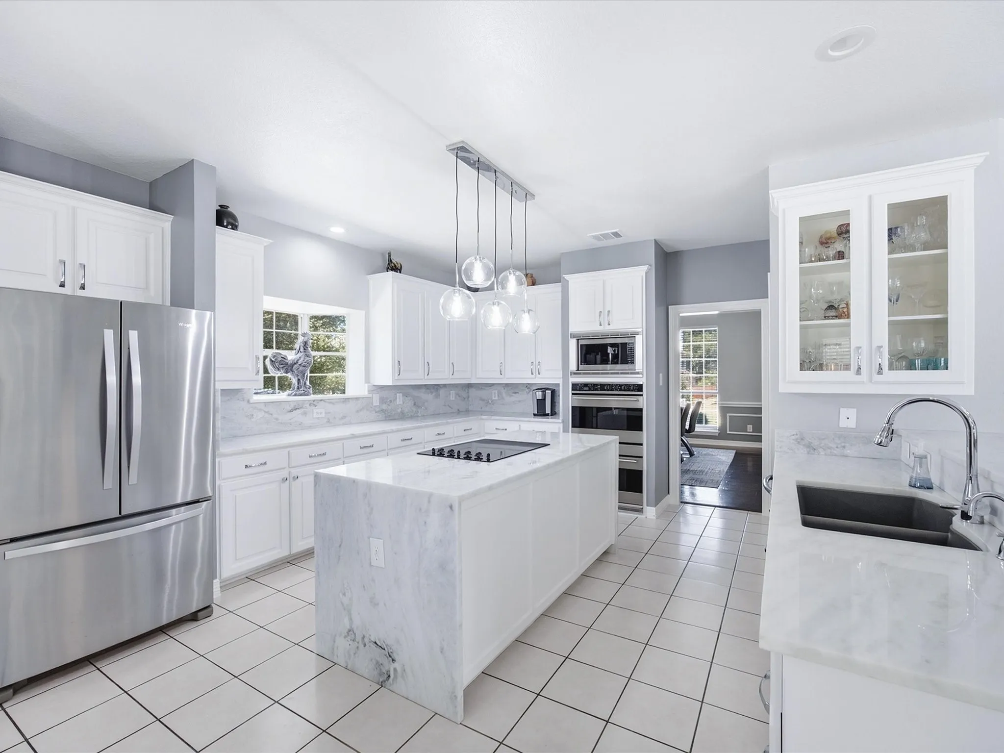 White cabinetry and light-toned countertops, featuring a kitchen island with cooktop