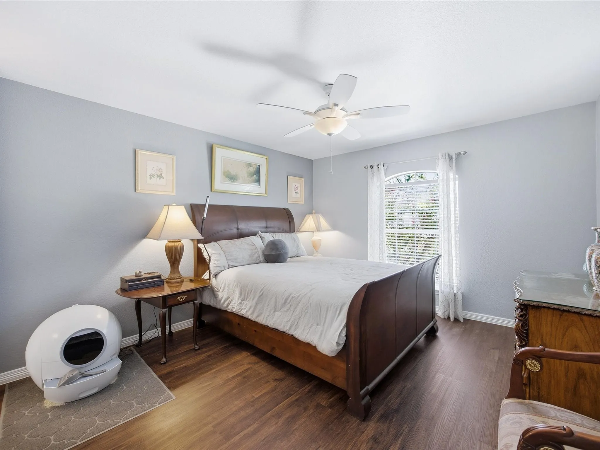 Wood-finish flooring, light grey wall paint, and a ceiling fan with integrated lighting
