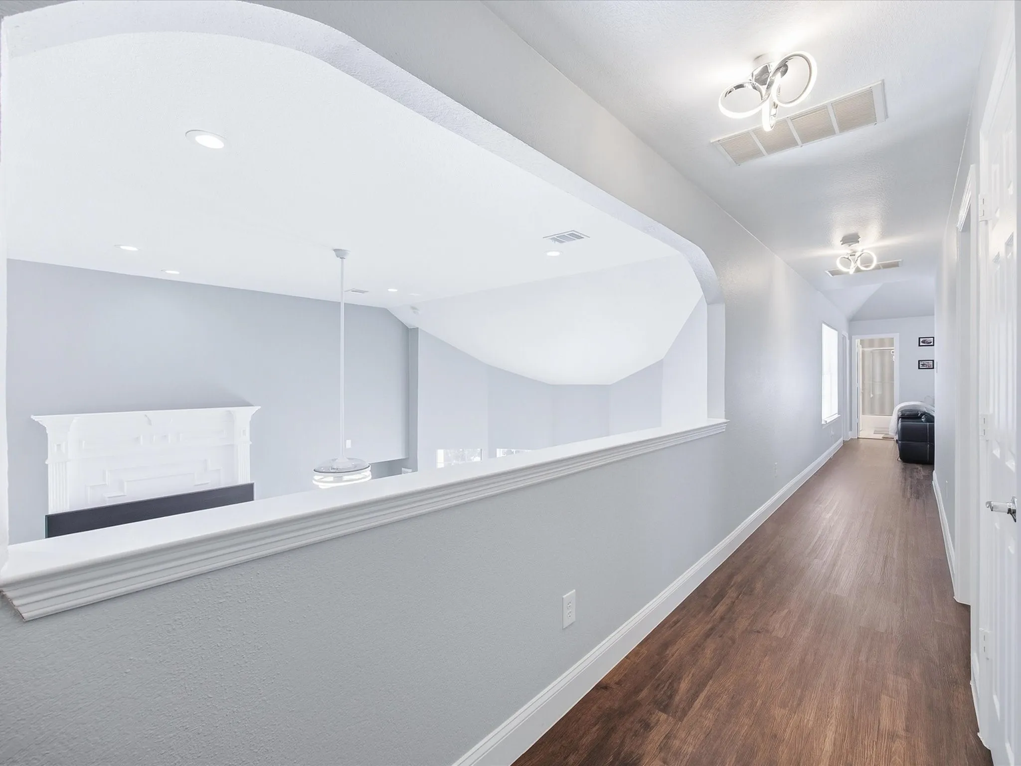 Upstairs hallway featuring wood-finish flooring, recessed lighting, and an arched wall opening