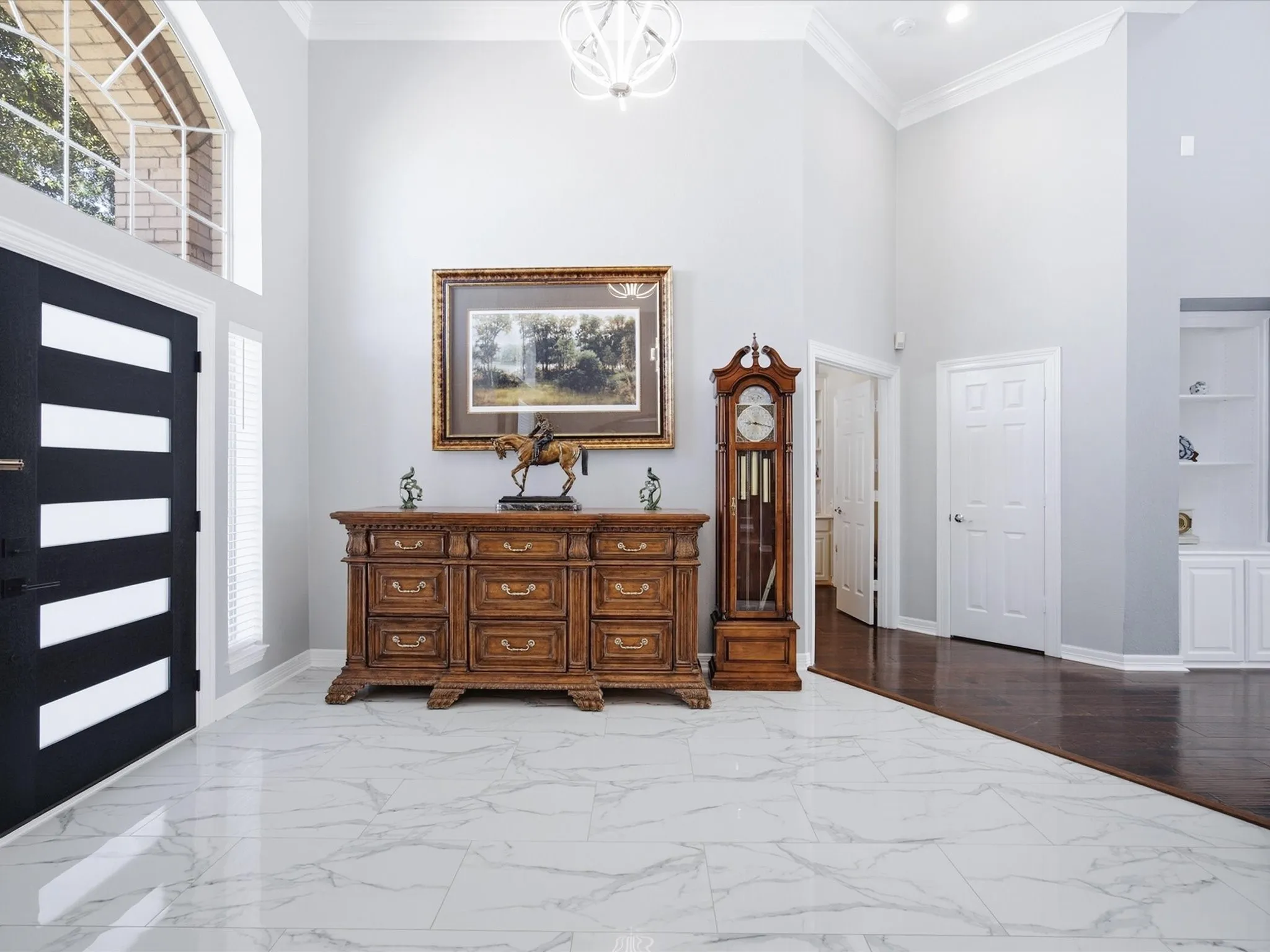 Two-story entry with a contemporary chandelier, marble-look tile flooring, and an arched transom window