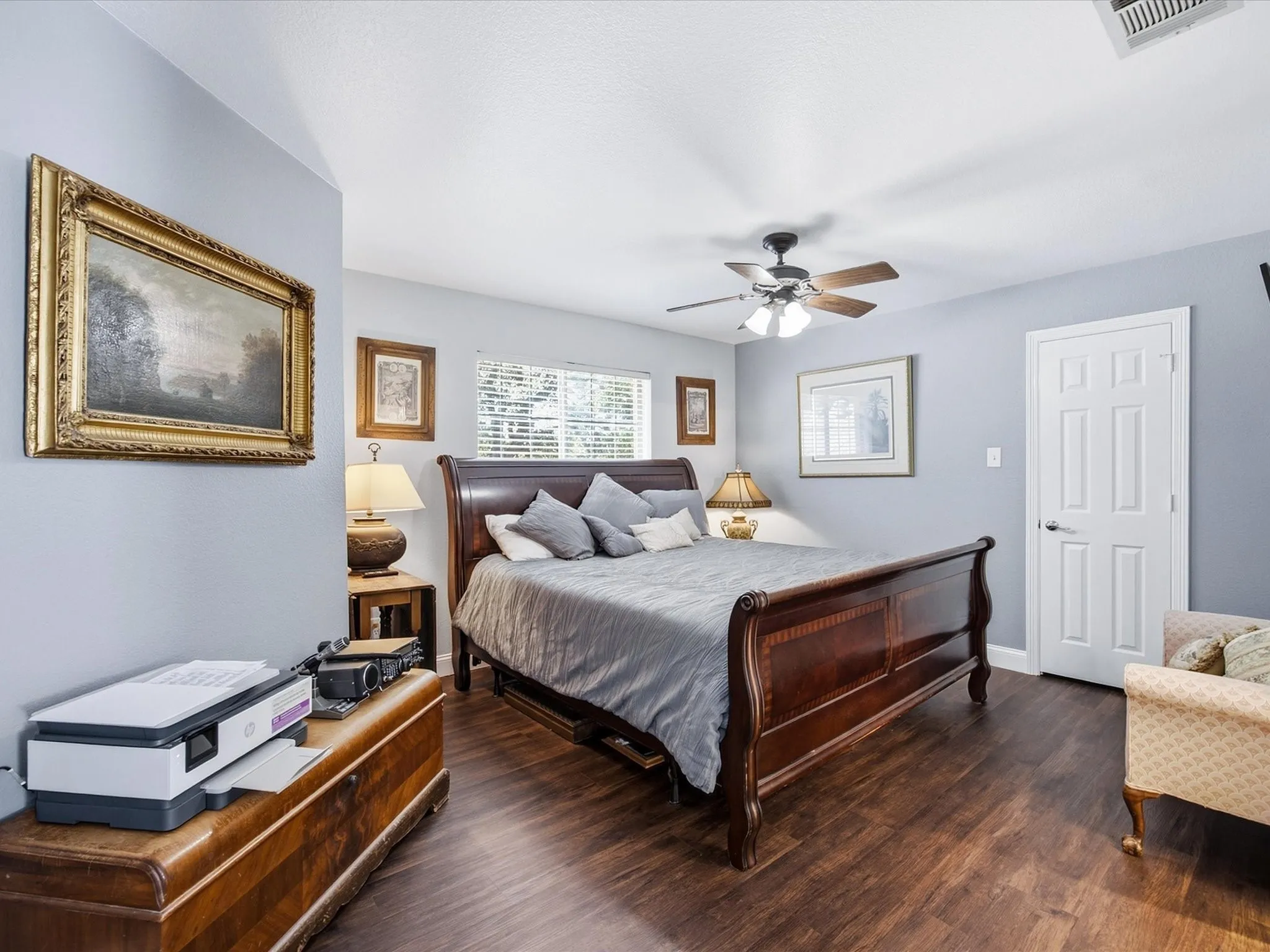 Wood-finish flooring throughout, ceiling fan with integrated lighting, and a window with horizontal blinds