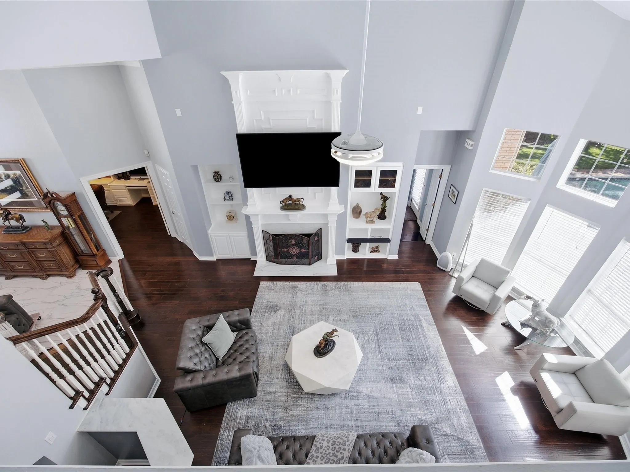 Two-story living area with high ceilings, dark wood-finish flooring, and a prominent fireplace with a decorative mantel