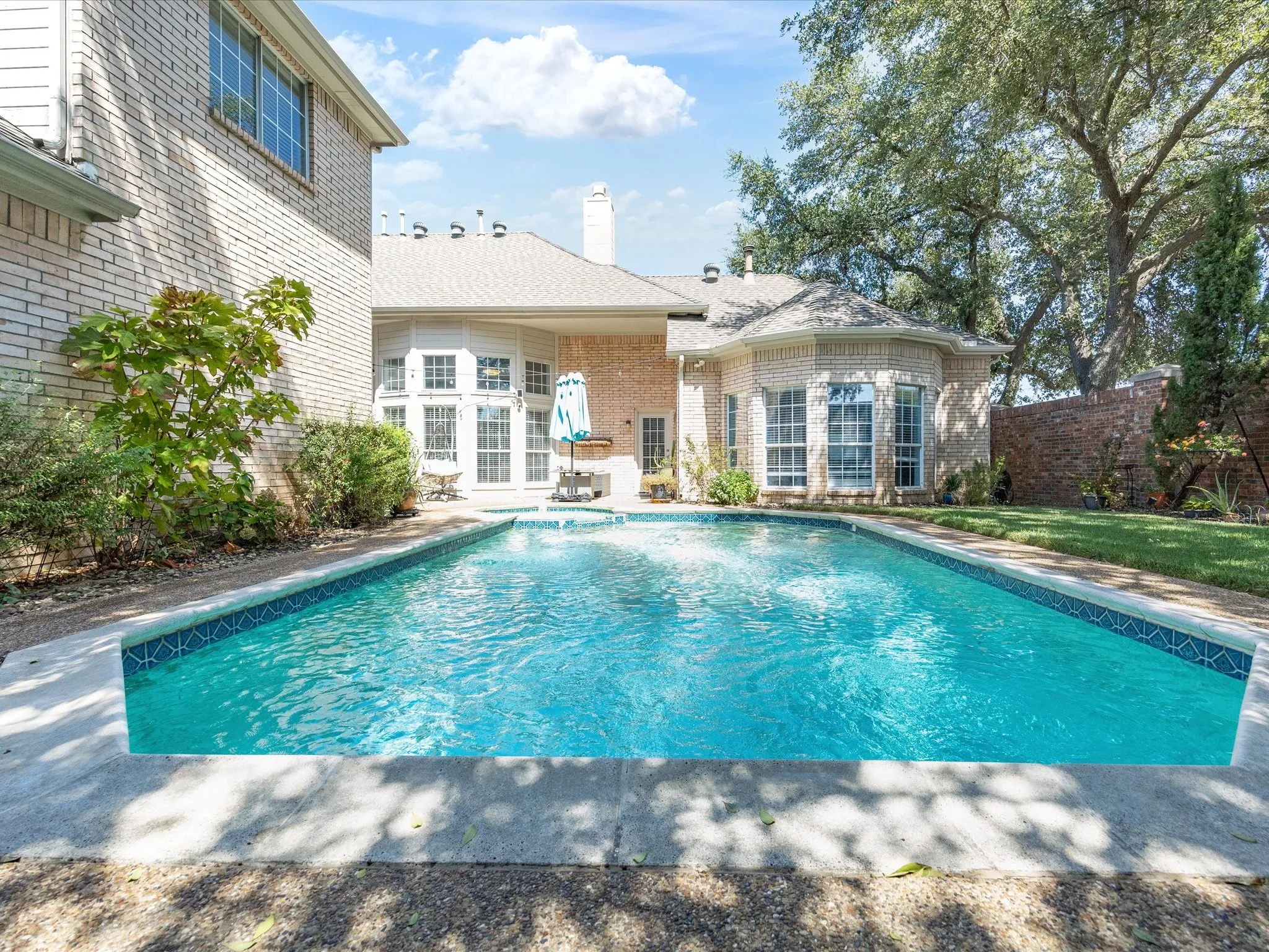 Private swimming pool with integrated water feature, surrounded by a concrete patio