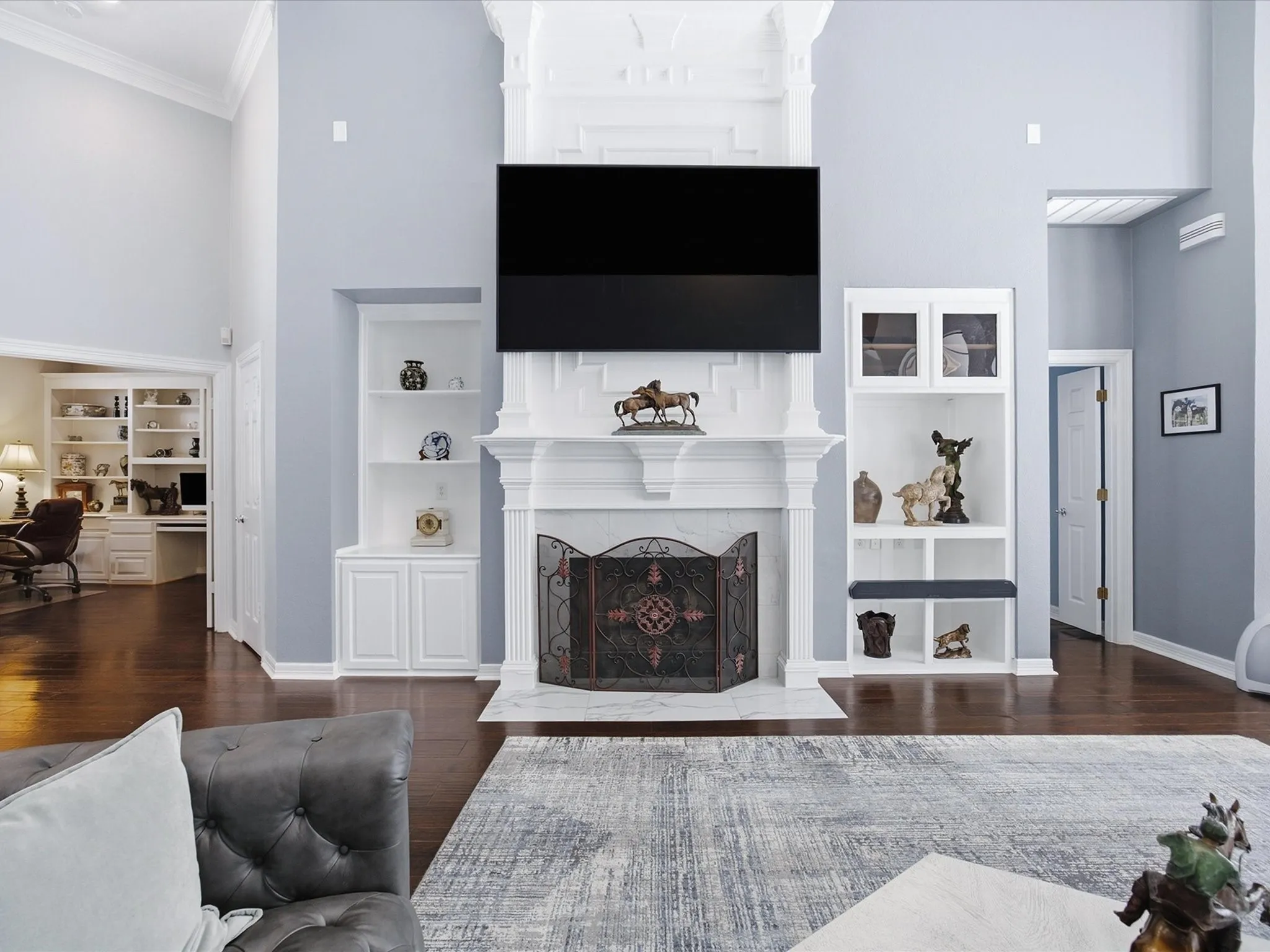 Great room featuring a prominent fireplace with a detailed mantel, flanking built-in shelving, vaulted ceilings, and wood-finish flooring