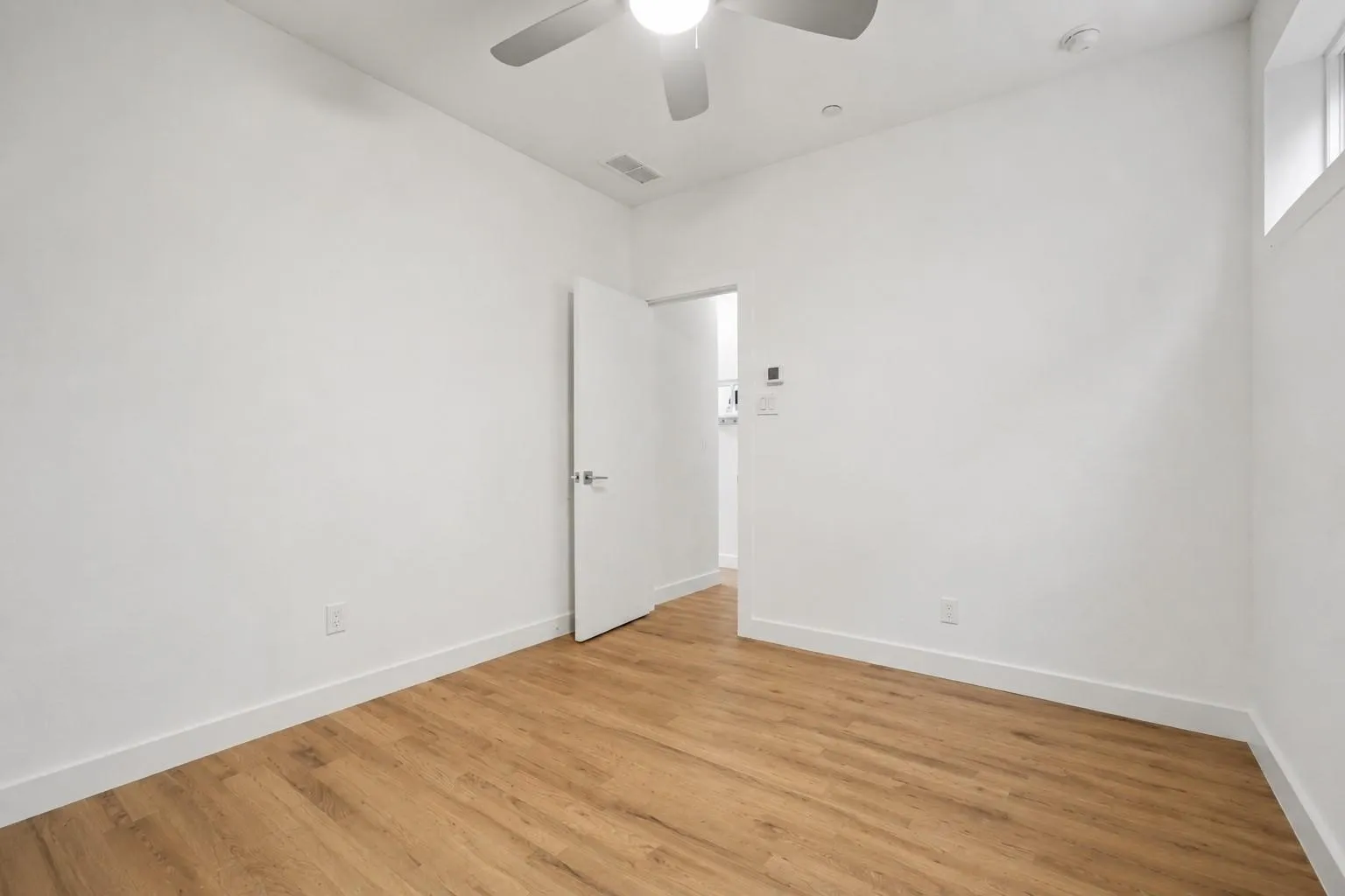 Hardwood-style flooring, white walls, ceiling fan, transom window, and recessed lighting