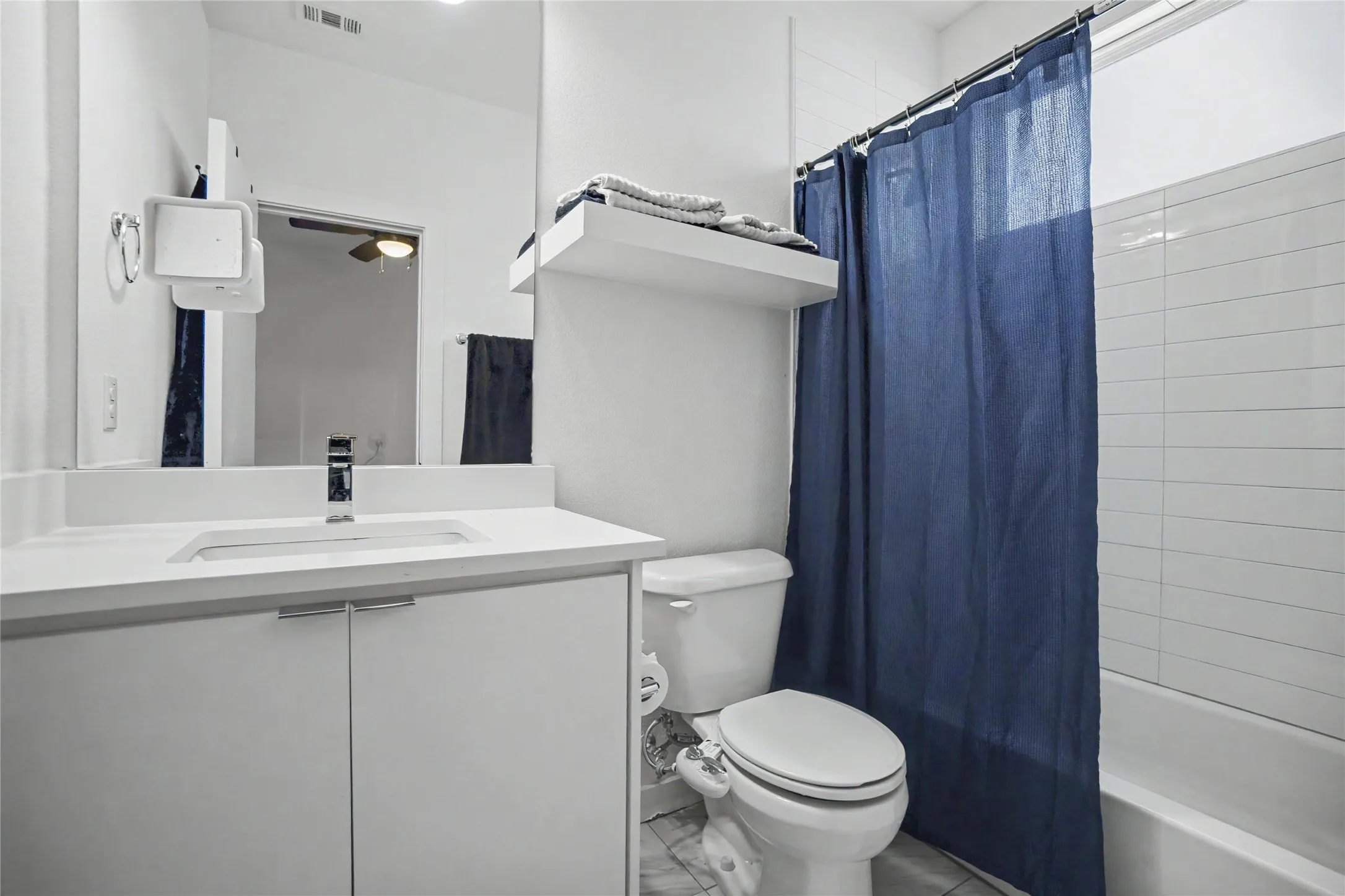 White vanity with integrated sink, chrome faucet, white countertop, and storage cabinetry