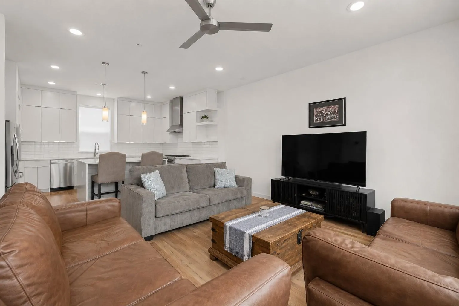 Open-concept living space with wood-finish flooring, recessed lighting, and a ceiling fan