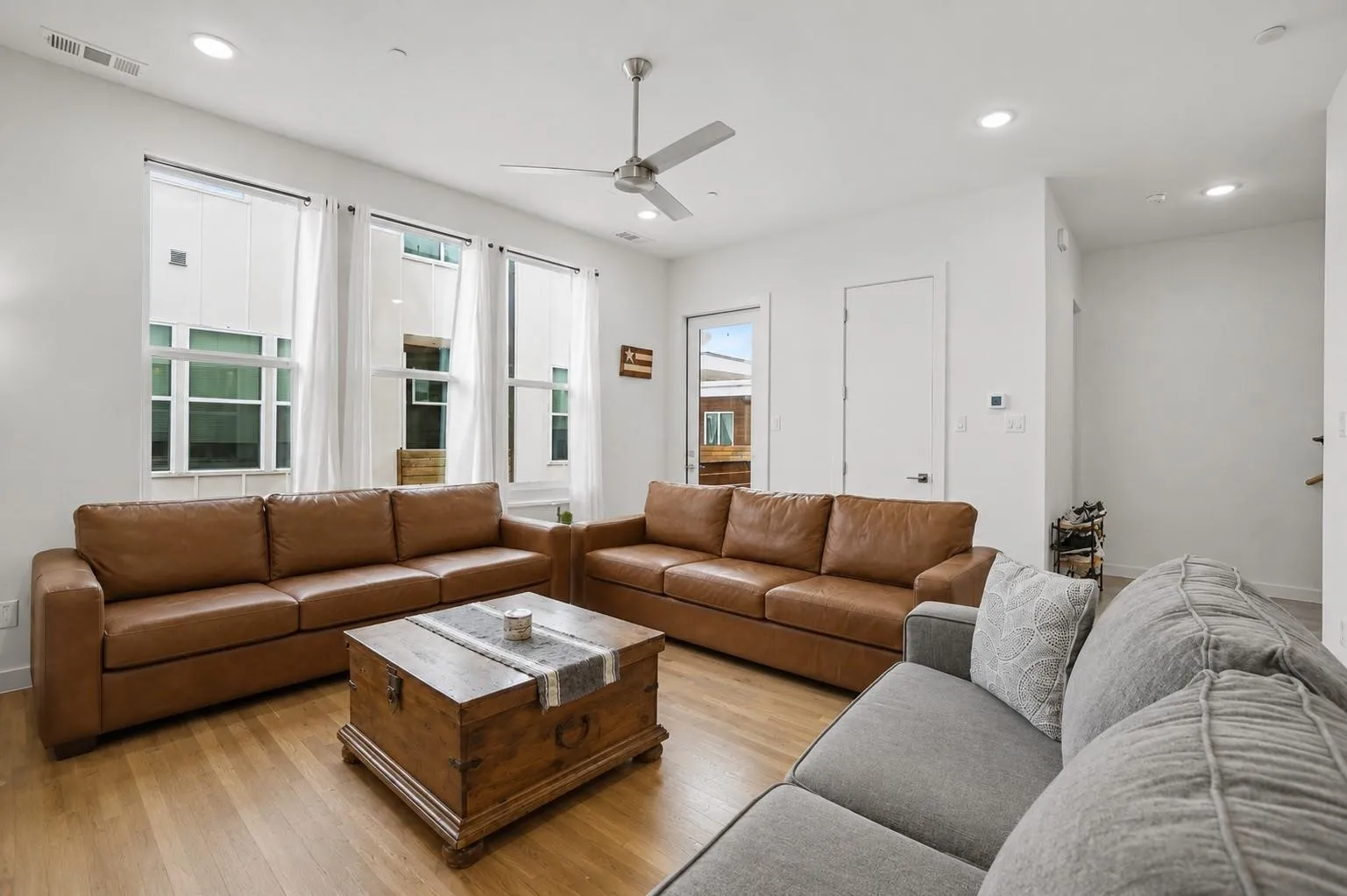 Recessed lighting, light wood-finish flooring, three vertical windows, ceiling fan, and white walls
