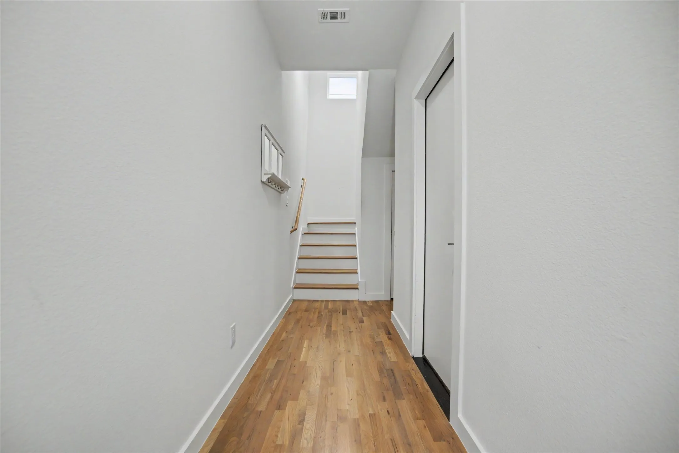 Hardwood flooring, painted white walls, recessed lighting, and a staircase with wood treads and a wood handrail