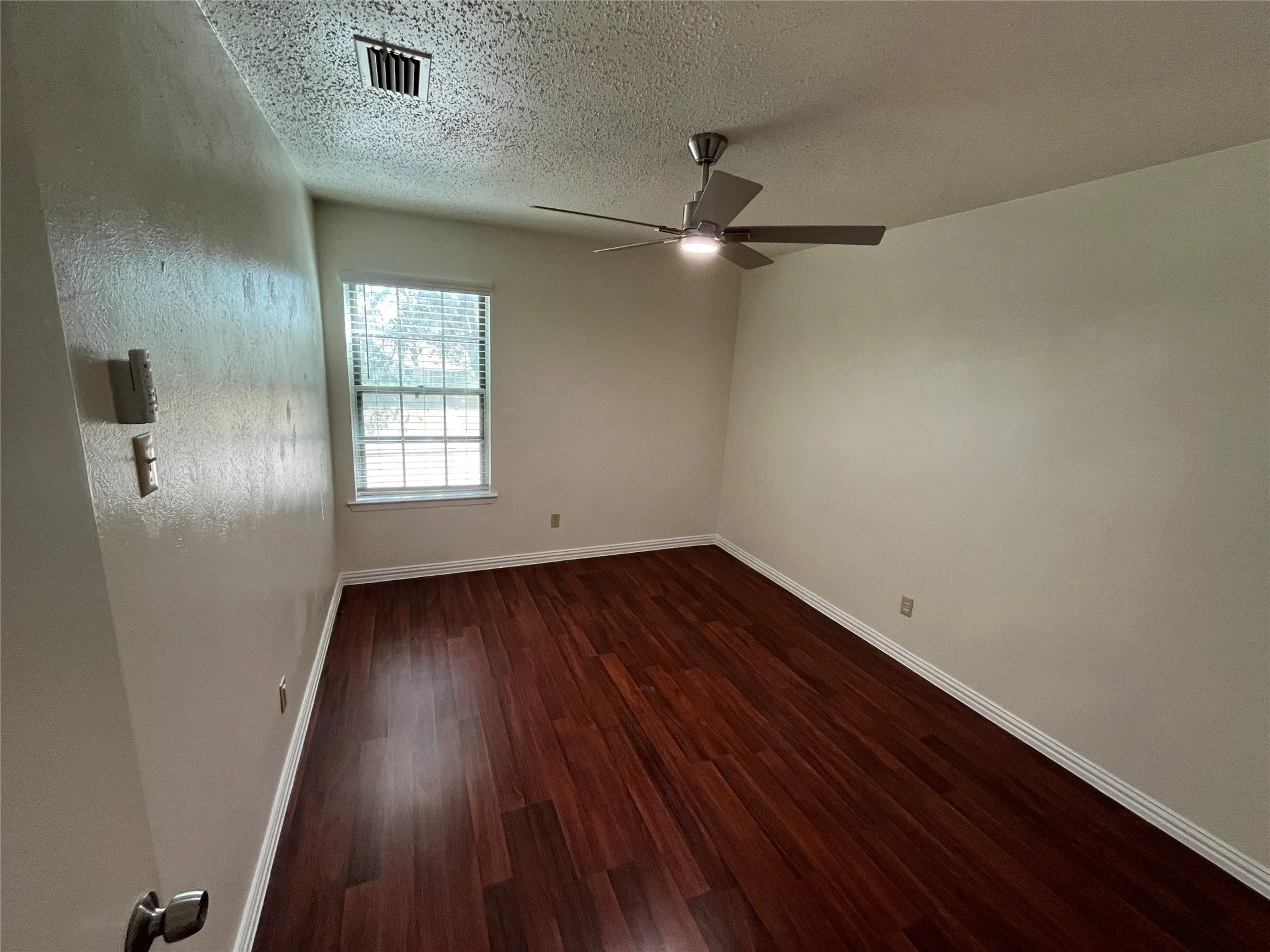 Wood-finish flooring, single window with blinds, ceiling fan, and light-toned wall paint