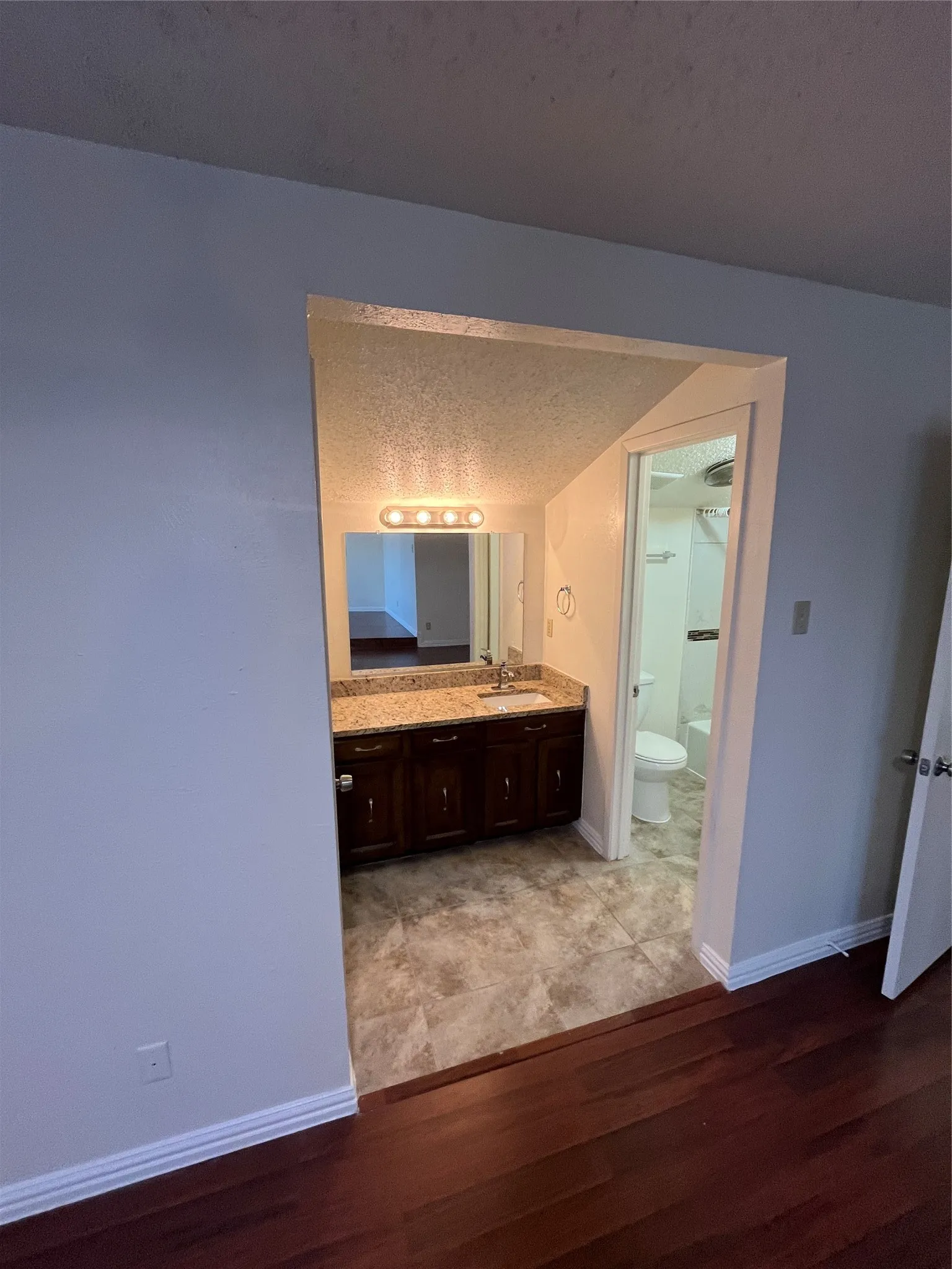 Bathroom vanity with granite countertop, integrated sink, and dark wood-finish cabinetry