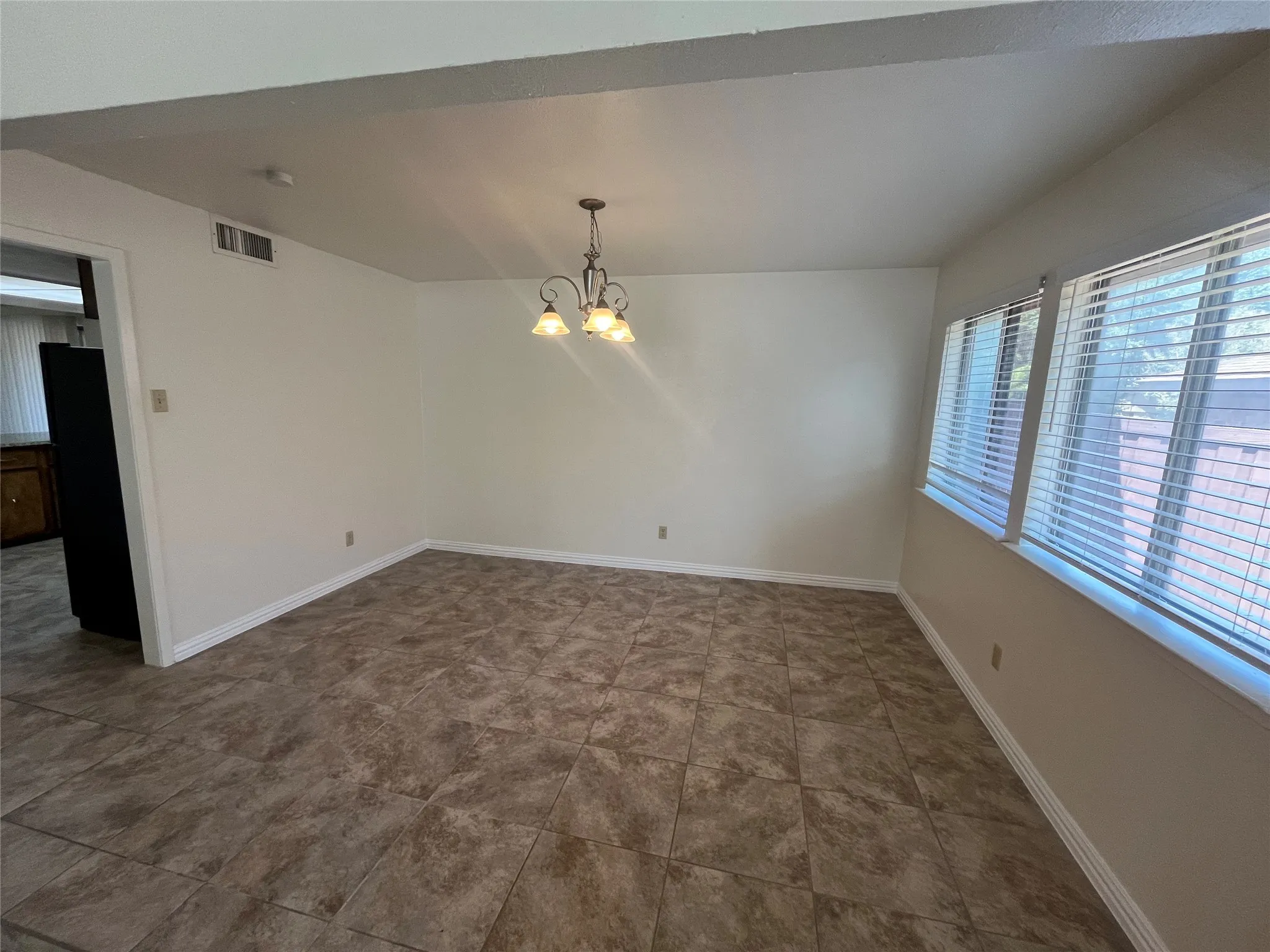 Tile flooring, white wall paint, window blinds, and a built-in ceiling light fixture