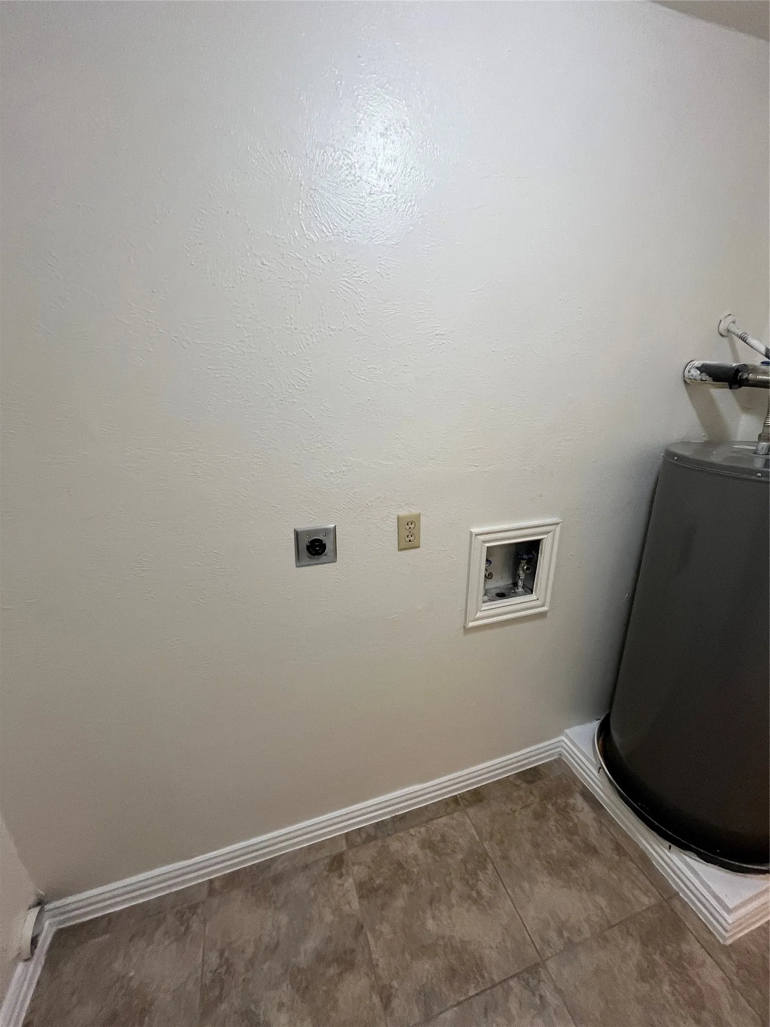 Utility area featuring a water heater, electrical outlets, and tile flooring