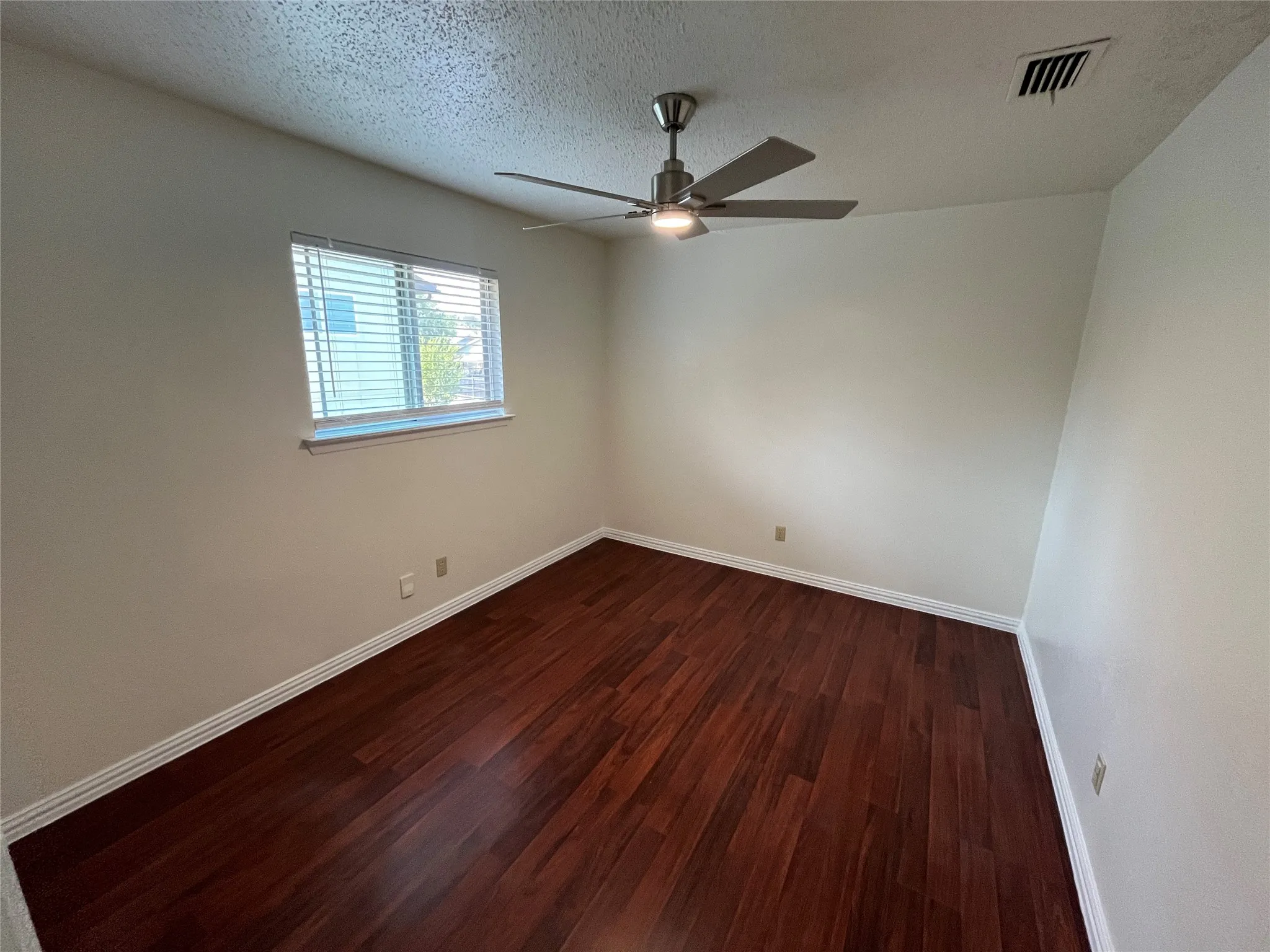 Wood-finish flooring, neutral wall tones, and a ceiling fan with integrated lighting