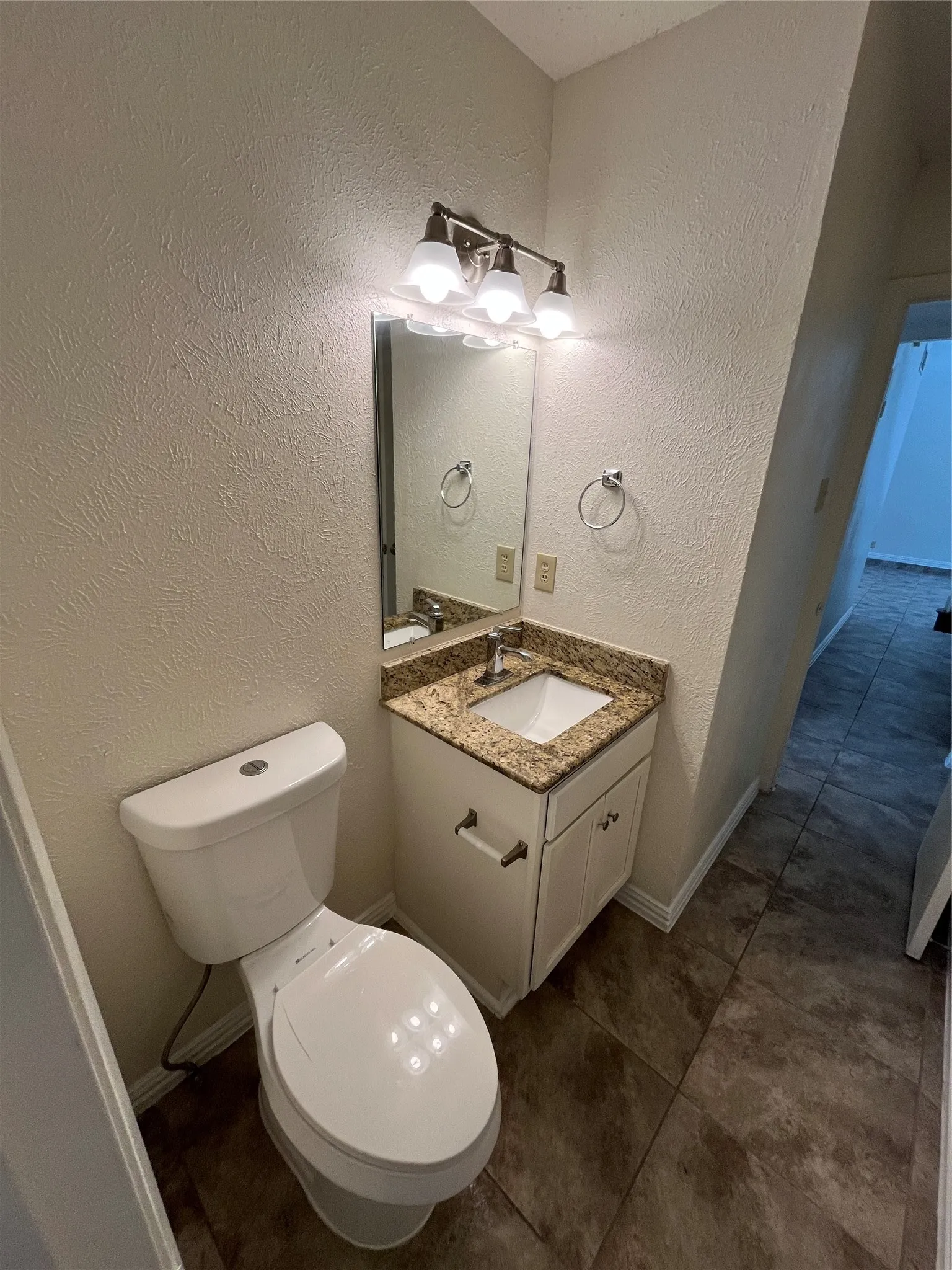 Vanity with a granite-style countertop, undermount sink, and white cabinetry with brushed nickel hardware