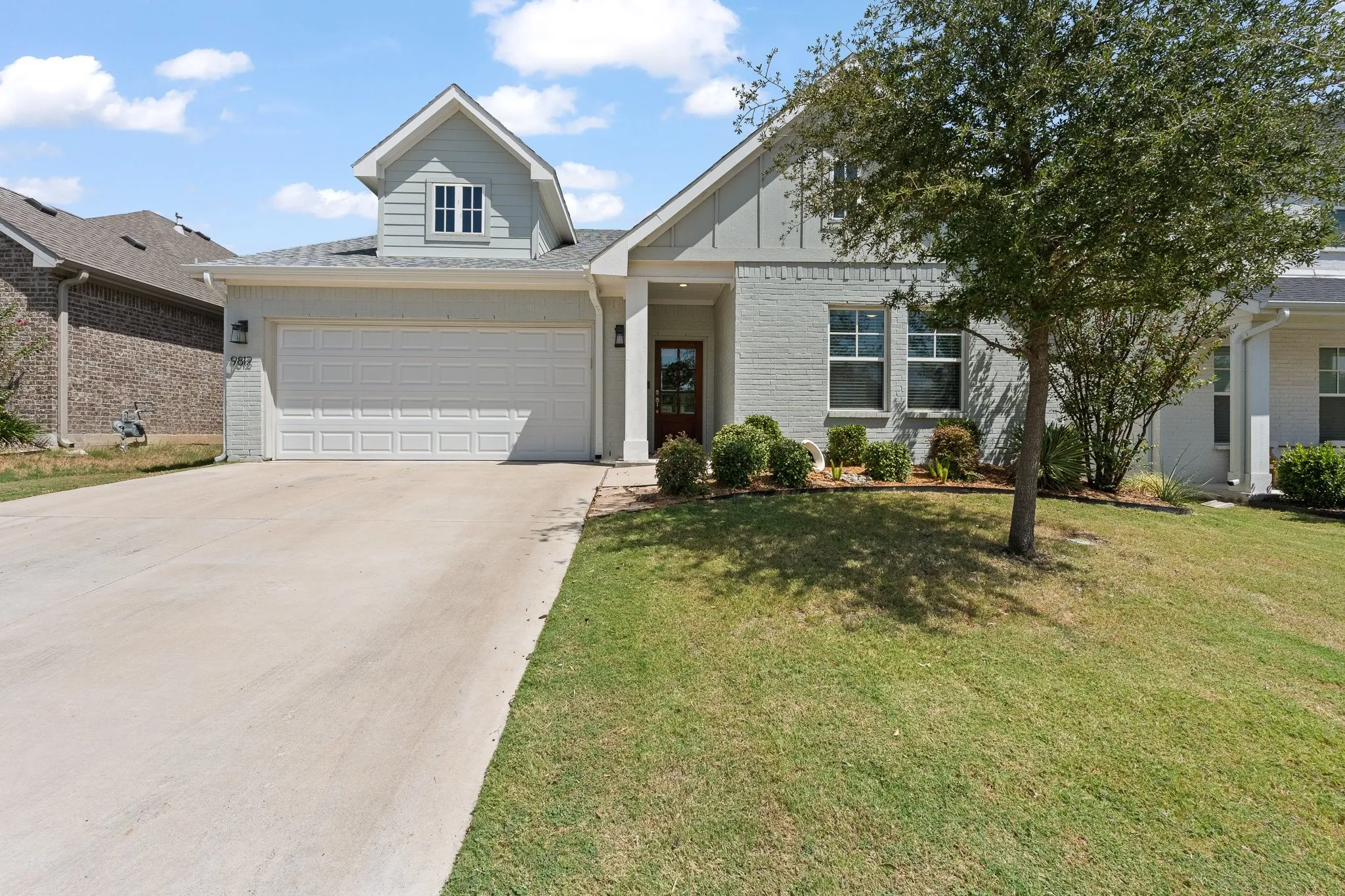 Charming exterior featuring painted brick, modern farmhouse-inspired details, an attached two-car garage, and a welcoming covered entry in Skyline Ranch.