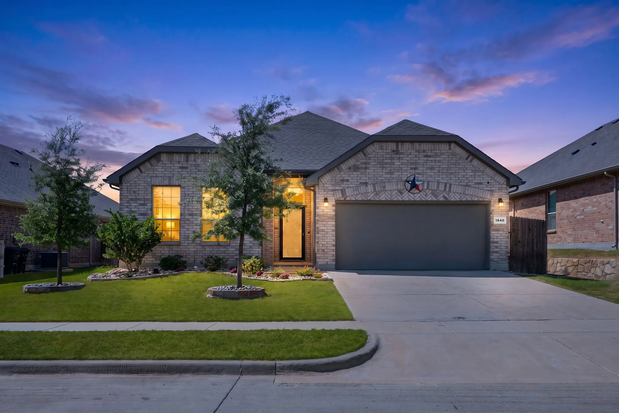 Brick facade, concrete driveway, attached garage, front yard with landscaping, covered entry
