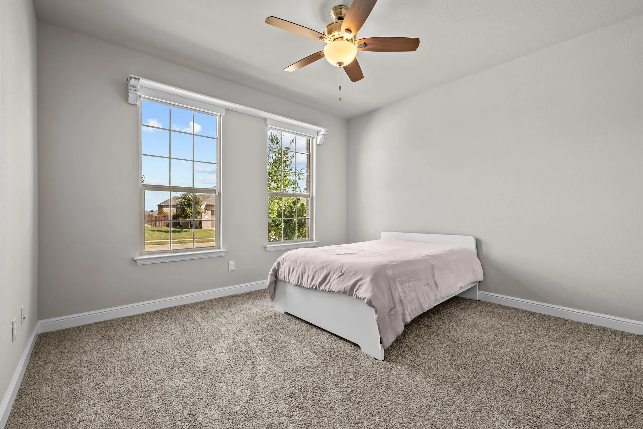 Carpeted room featuring two multi-pane windows, a ceiling fan with integrated lighting, and neutral wall tones