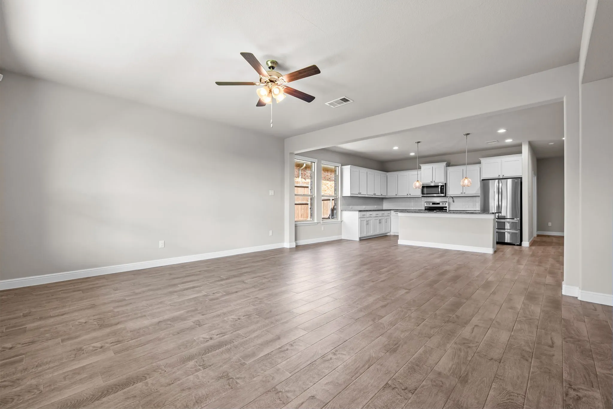 Open-concept living space with wood-finish flooring, a ceiling fan, and recessed lighting