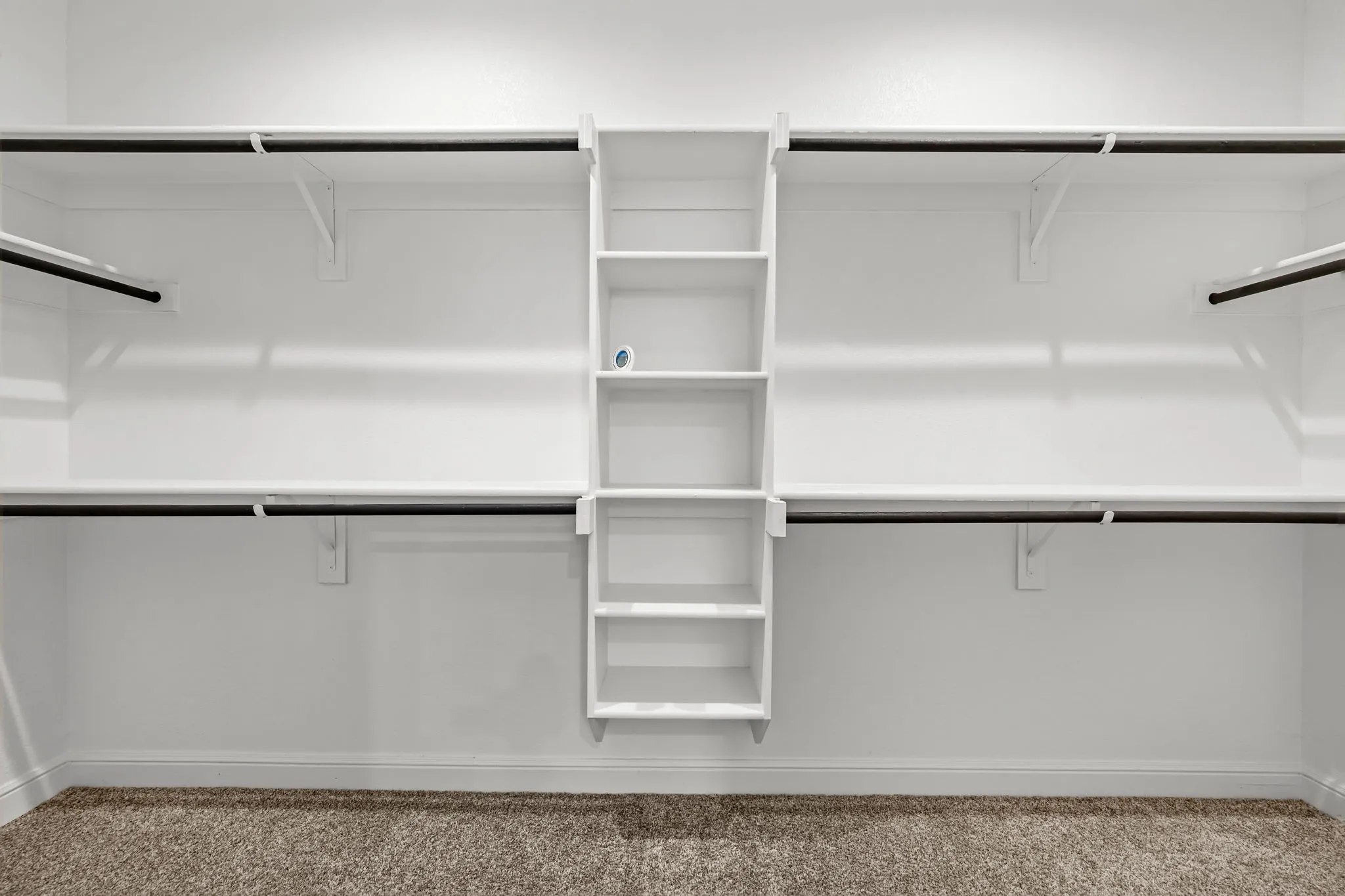 Built-in shelving with multiple levels, dual hanging rods, and carpet flooring