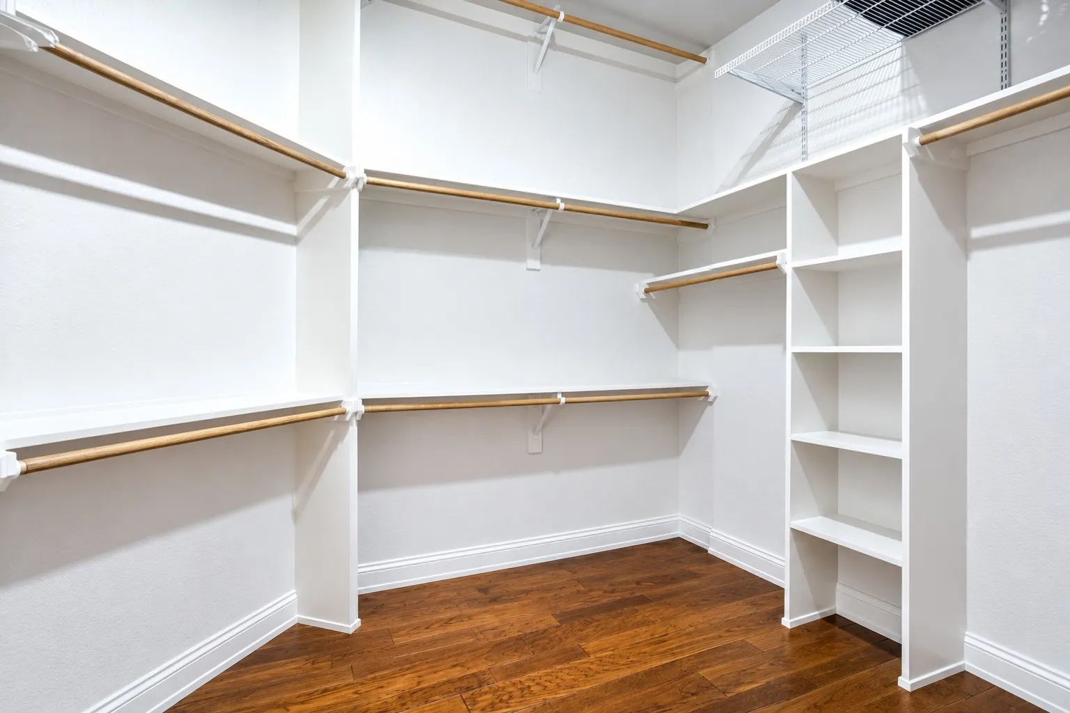 Primary walk-in closet located just off the primary bath. This image has been digitally rendered to remove personal belongings and show the closet vacant.bath.  This photo is an ai rendering to remove the current belongings and show the closet empty.