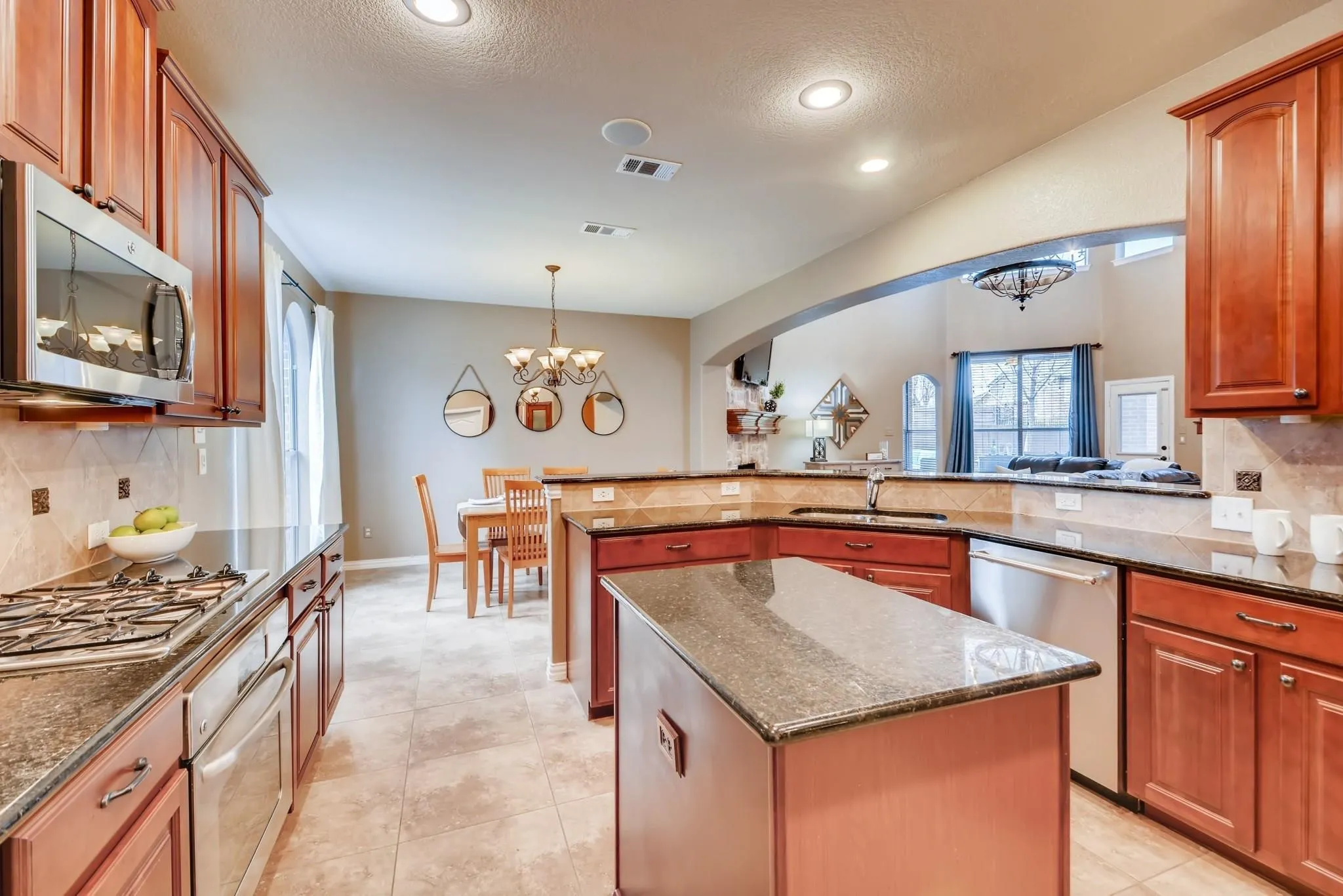 Kitchen featuring wood cabinetry, stainless steel appliances, granite countertops, and a central island