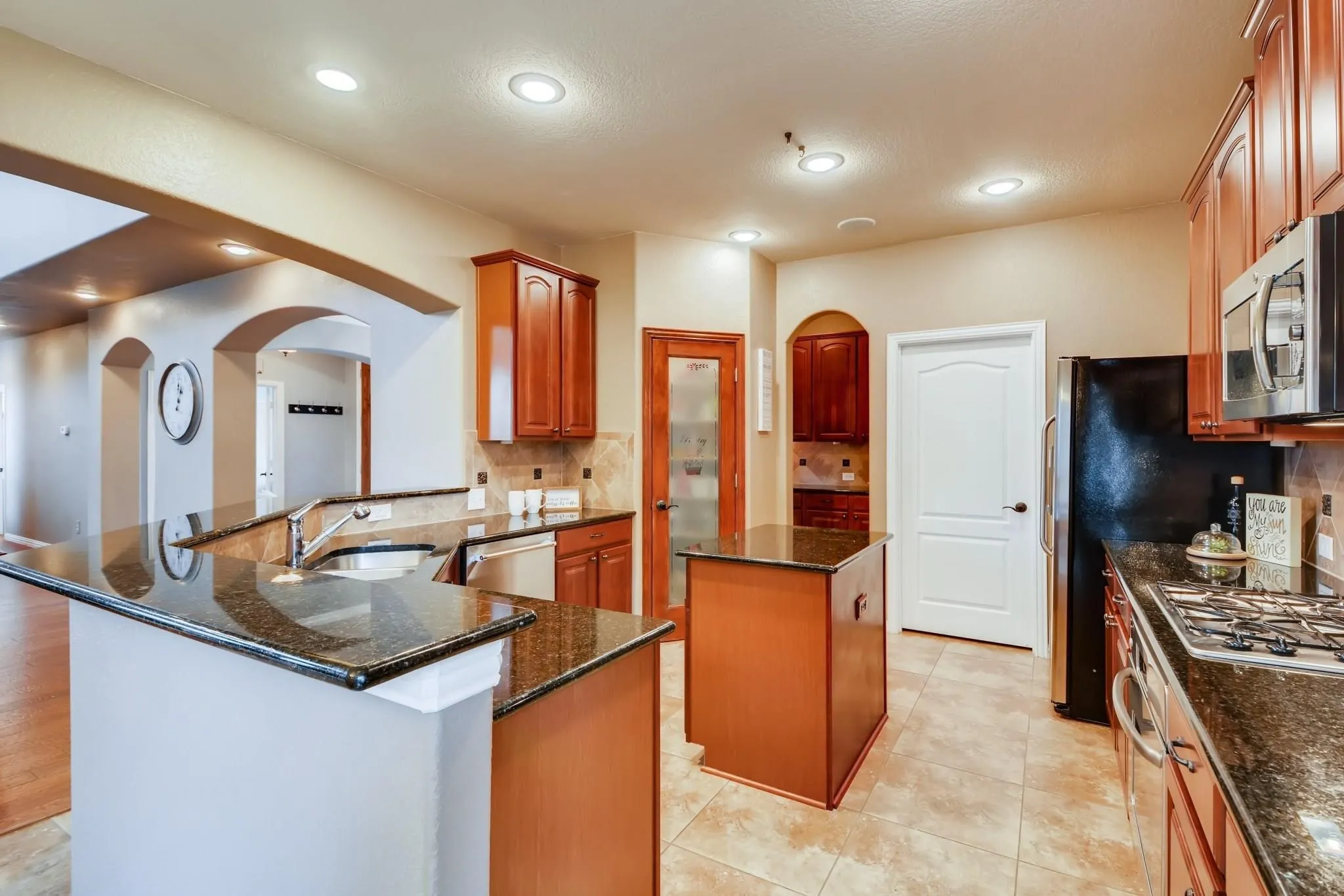 Kitchen with recessed lighting, granite countertops, wood cabinetry, and a central island