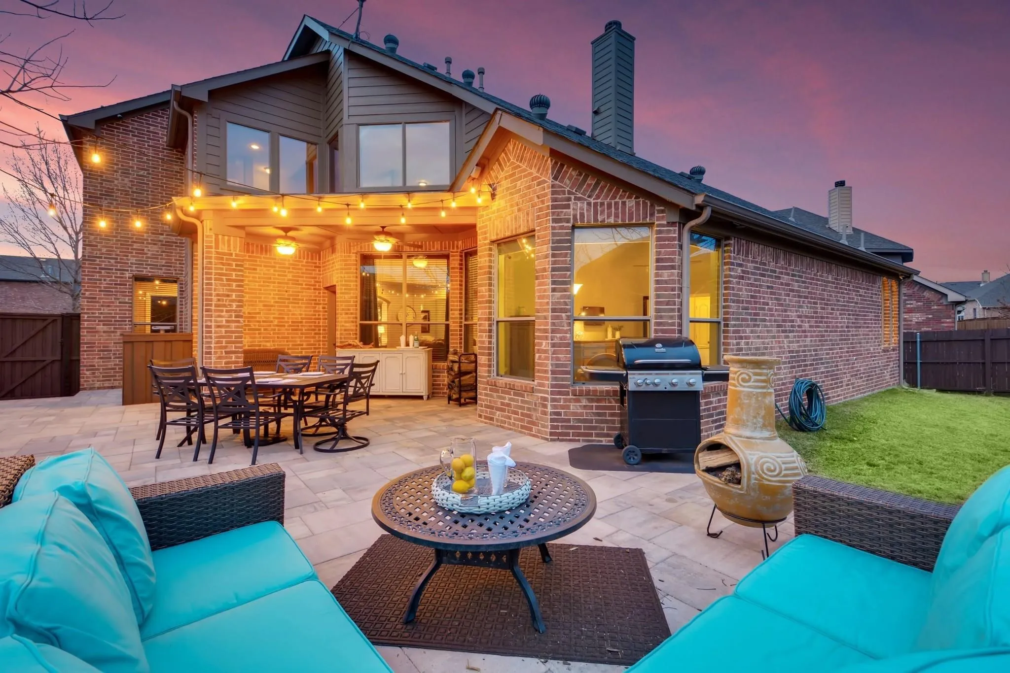 Expansive paver patio with a covered outdoor living area featuring integrated ceiling fans and lighting