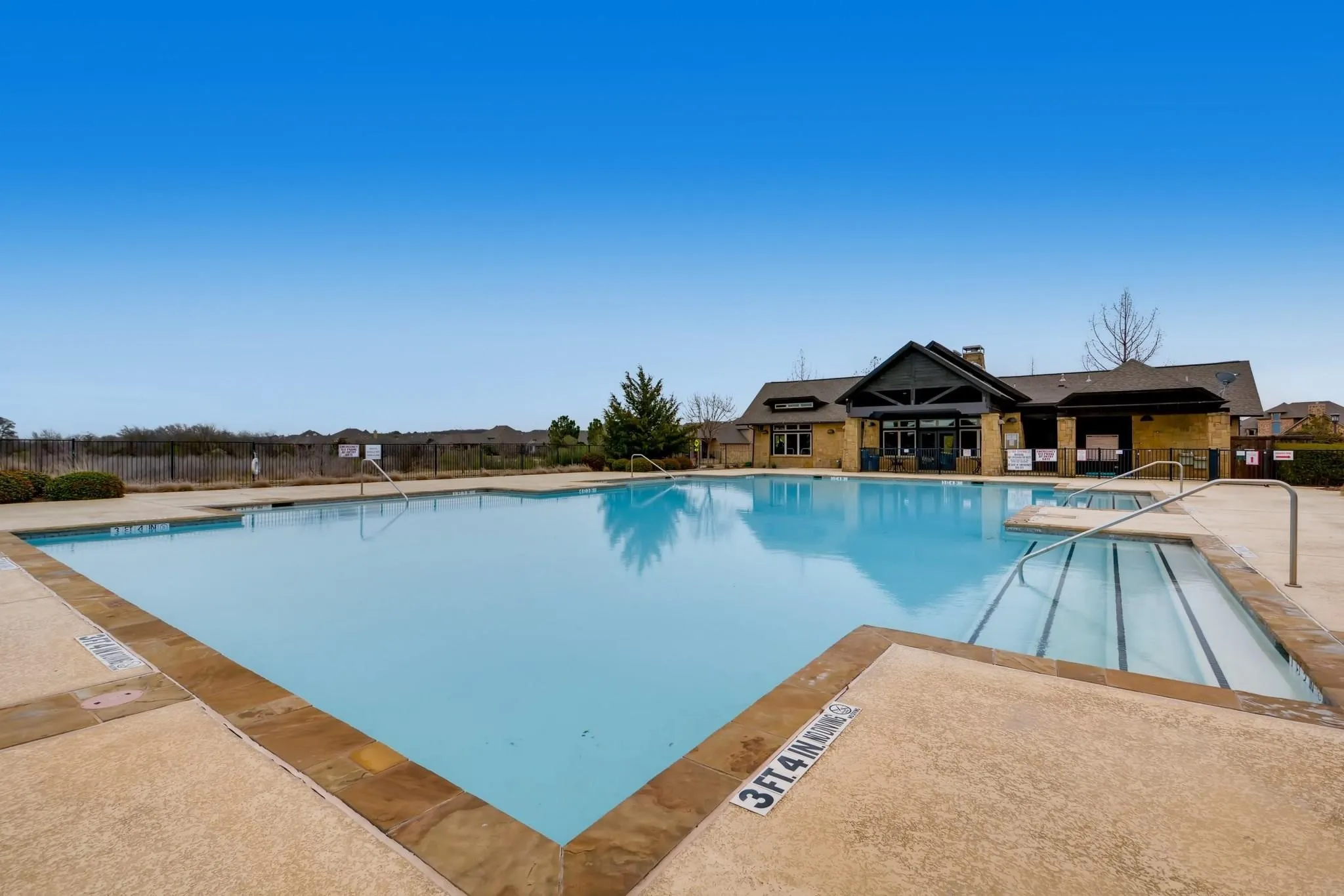Expansive outdoor swimming pool with integrated entry steps and a concrete deck with stone-look trim