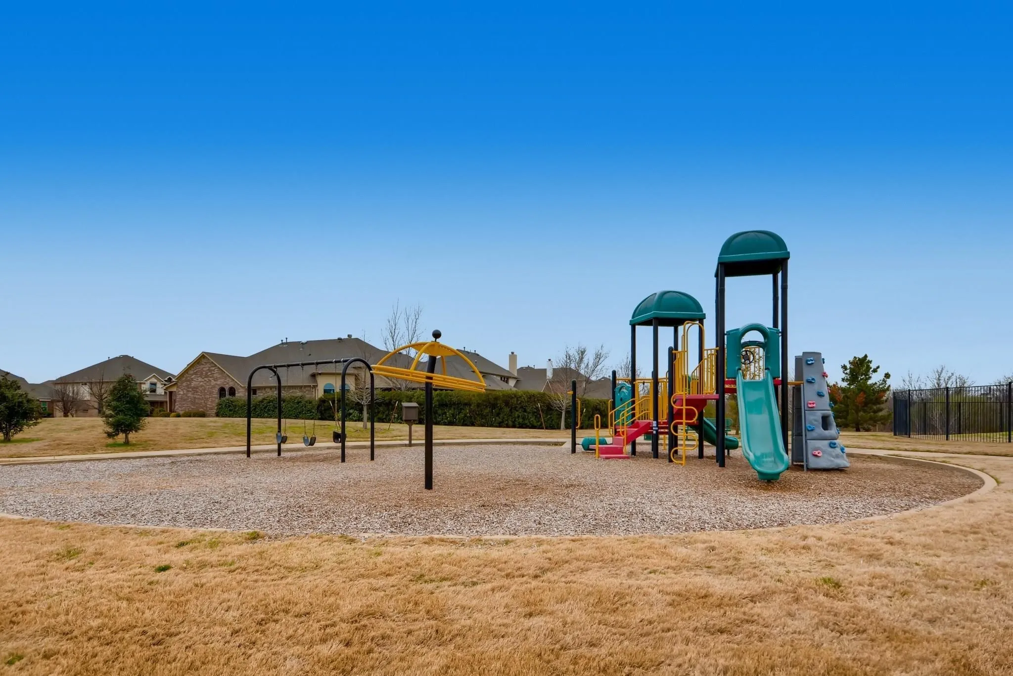 Playground area featuring multiple slides, climbing elements, and swings, set on a soft ground surface
