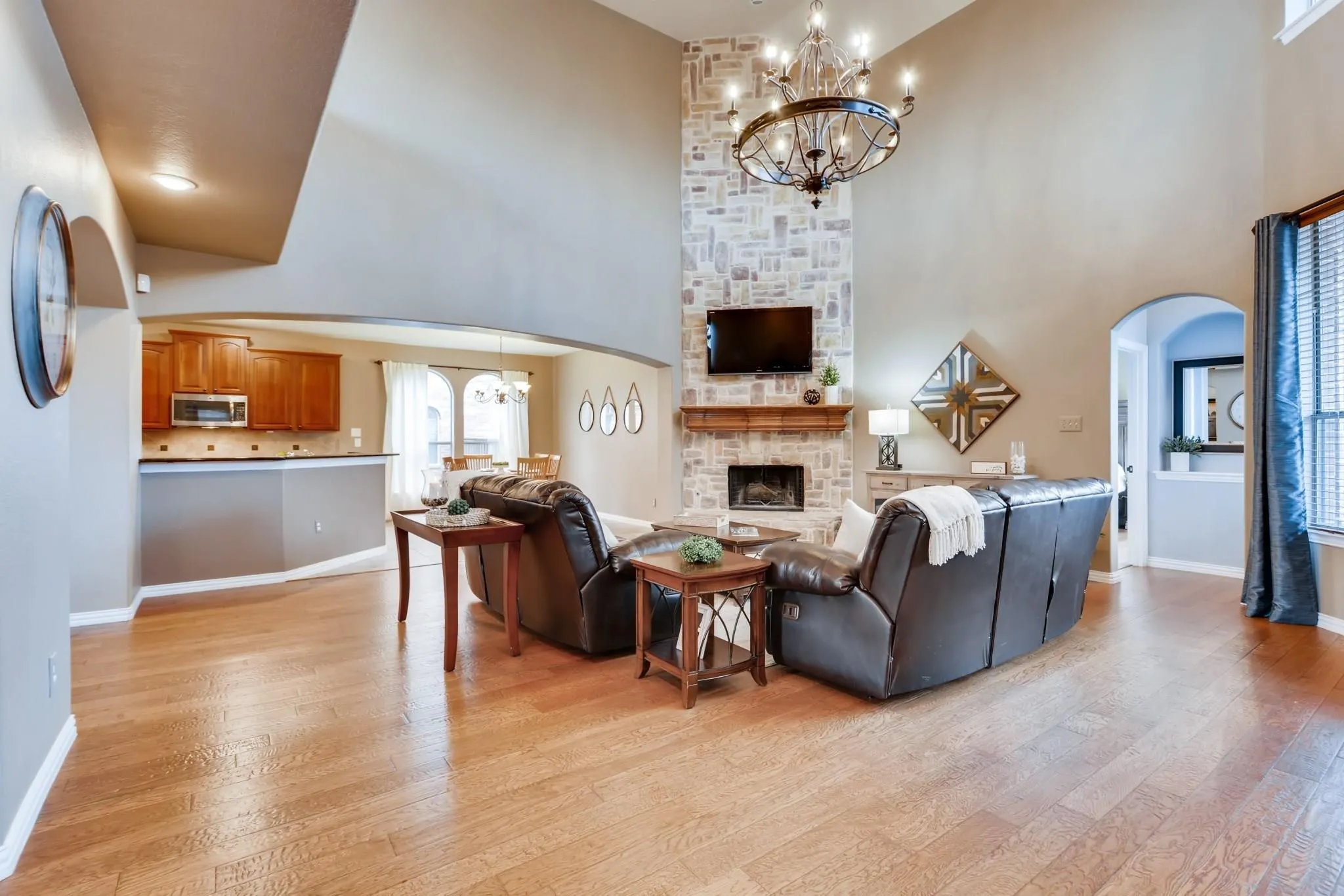 Hardwood-finish flooring throughout, two-story ceiling, stone-clad fireplace with mantel, archways, and a built-in kitchen peninsula