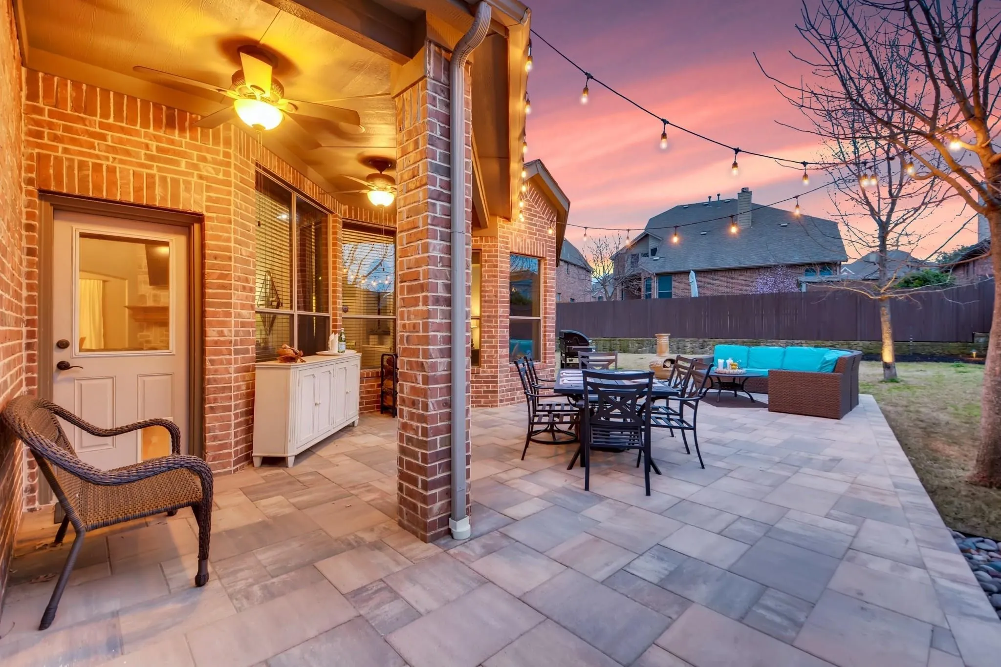 Brick exterior patio with ceiling fans, string lighting, and a paved hardscape