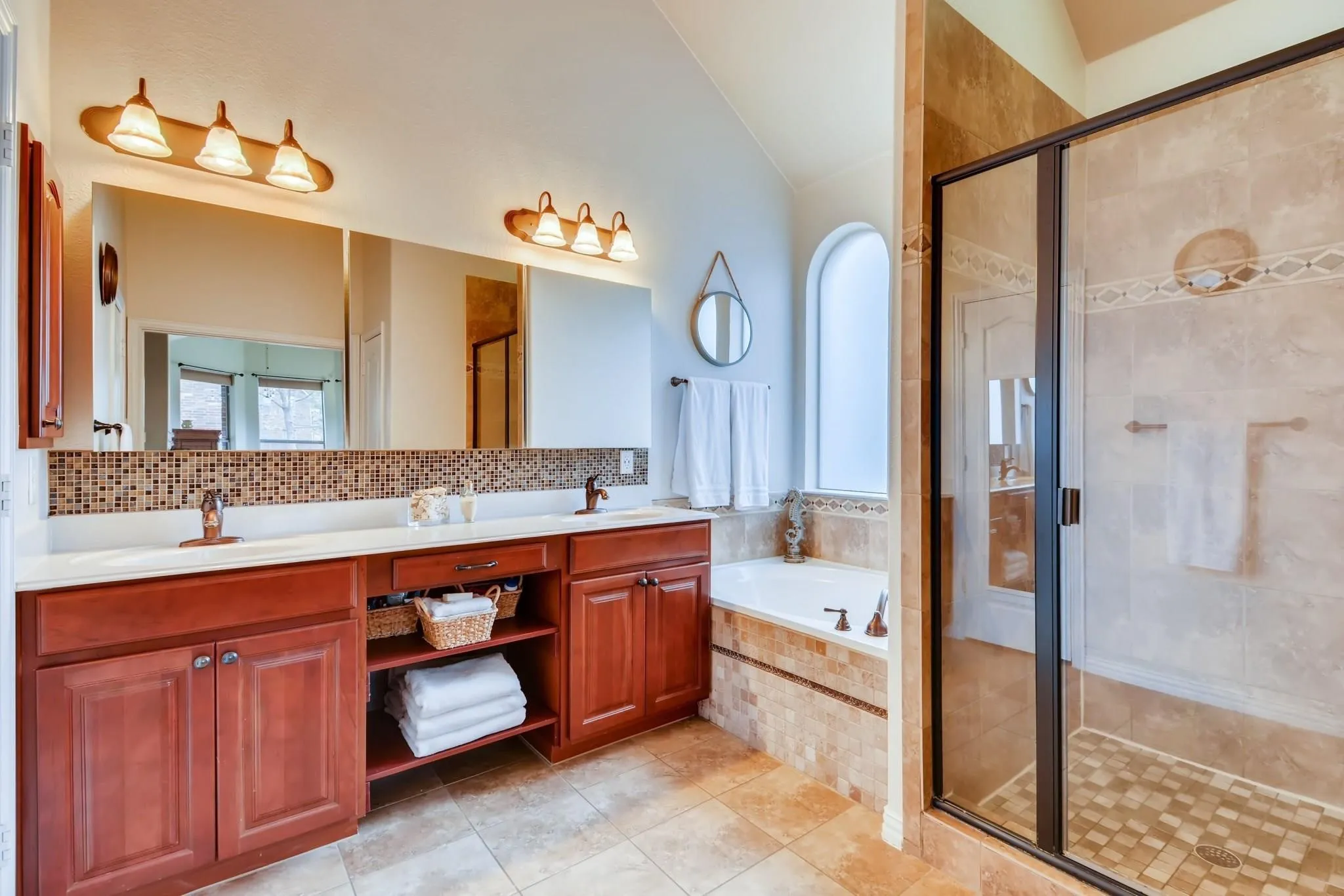 Dual vanity with wood-finish cabinetry, tile backsplash, and integrated sinks