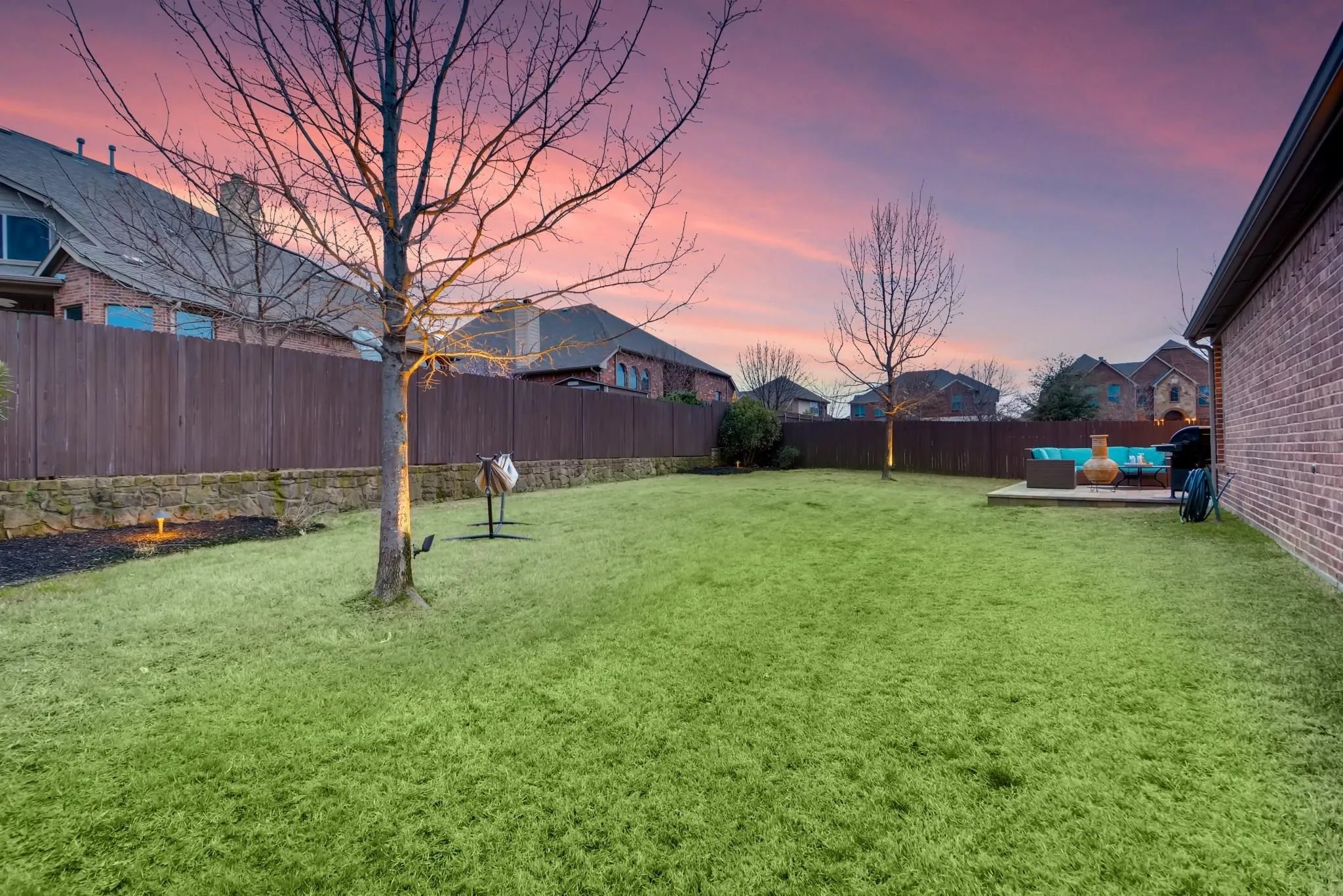 Expansive grassy lawn with a wood fence and stone retaining wall
