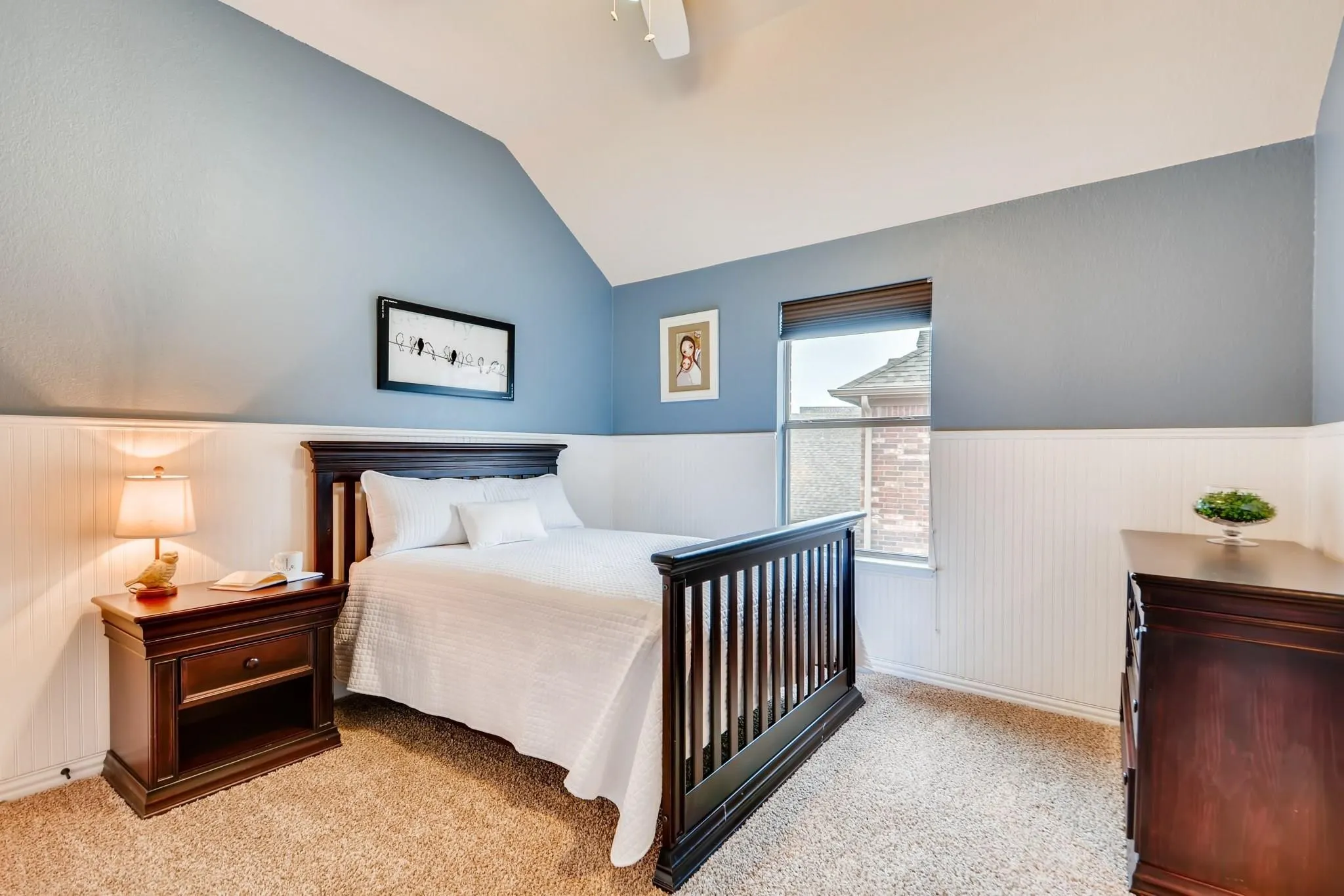 Vaulted ceiling with a flush-mount light, beadboard wainscoting, and a window with blinds