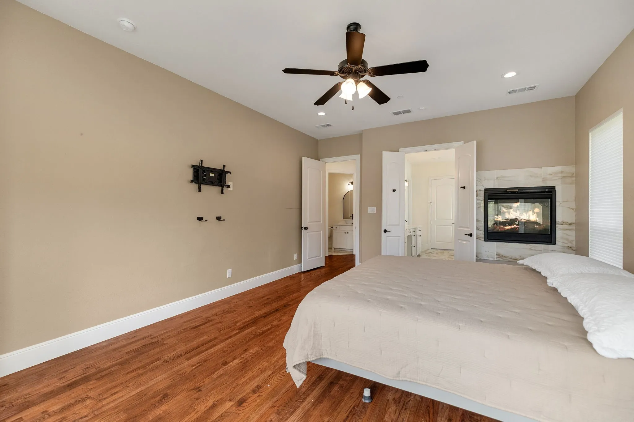 Wood-finish flooring, recessed lighting, ceiling fan, and a built-in fireplace with a stone surround