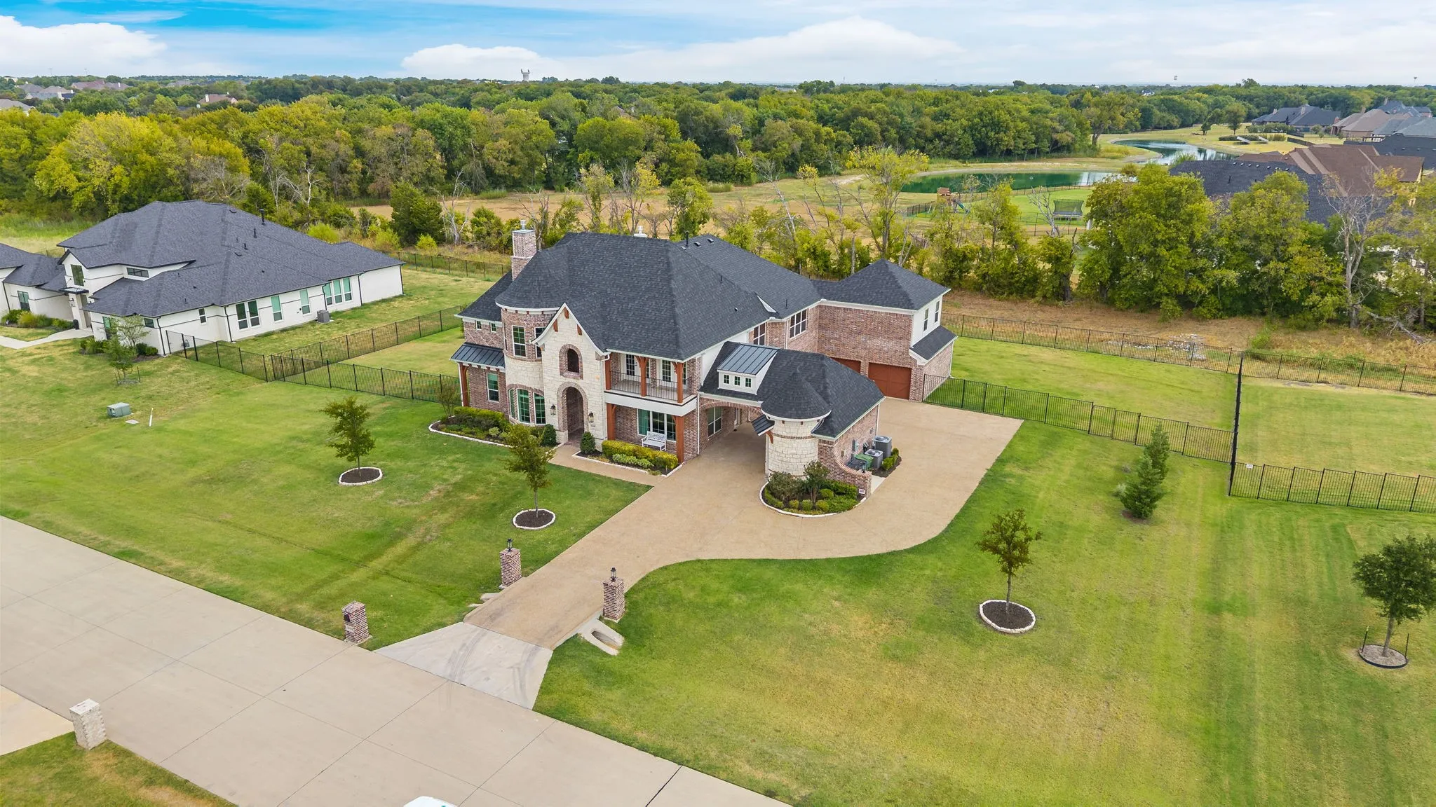 Stately residence featuring a brick and stone exterior, dark shingle roof, and a curved driveway
