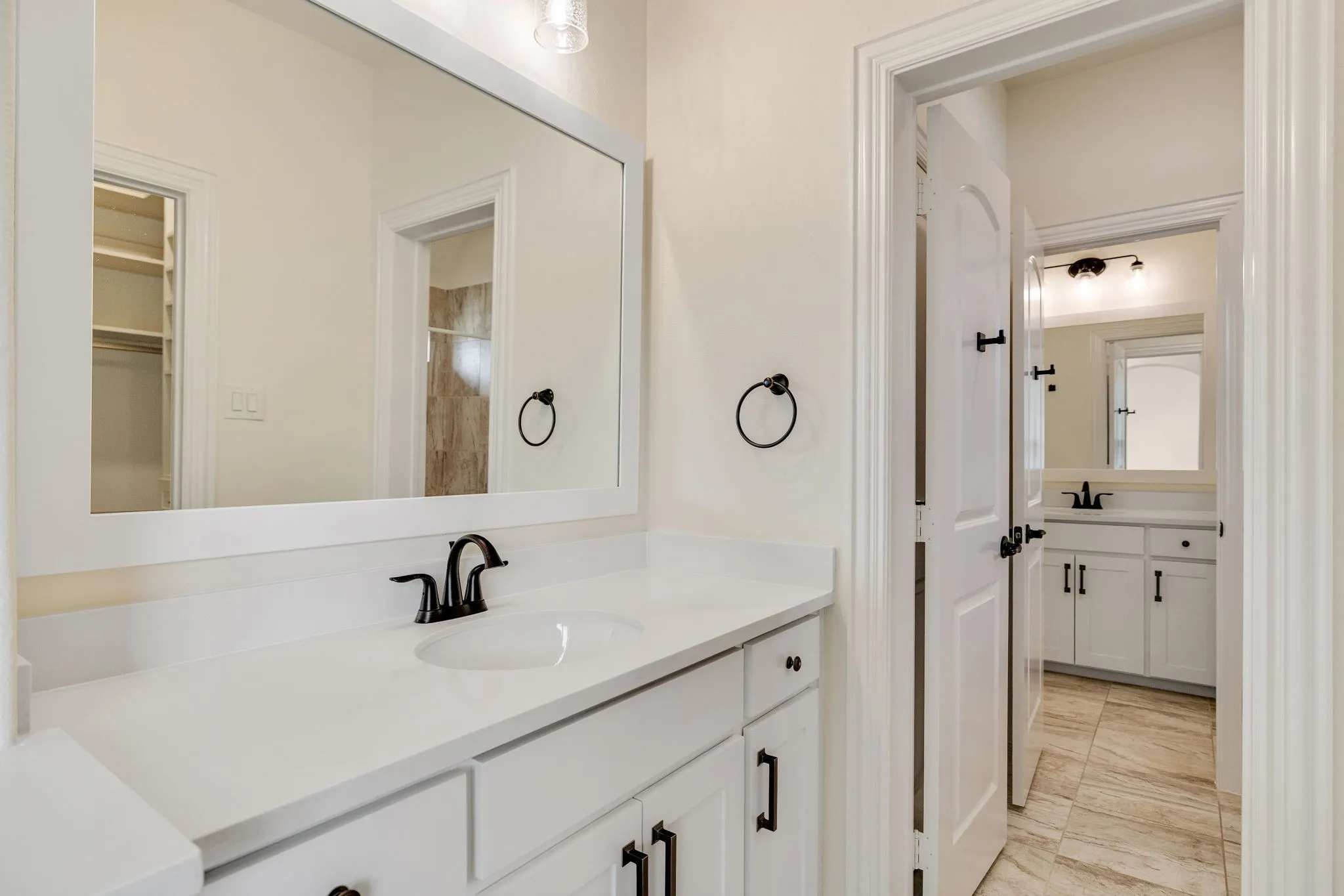 White vanity with integrated sink, matte black faucet, and white framed mirror