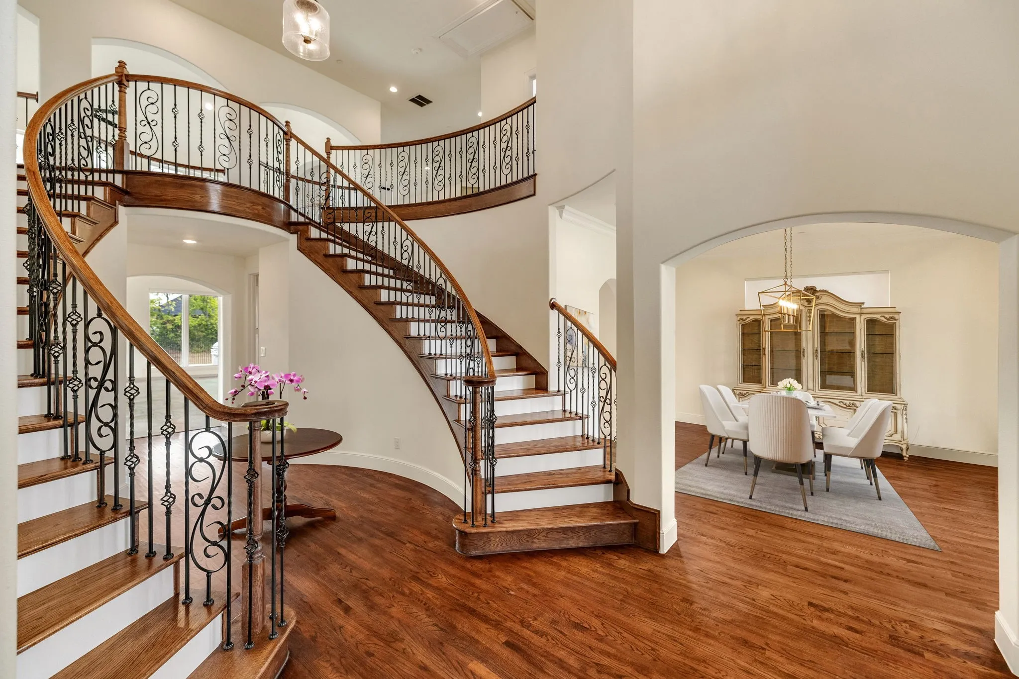 Grand two-story foyer featuring a curved staircase with wrought iron balusters and wood handrails