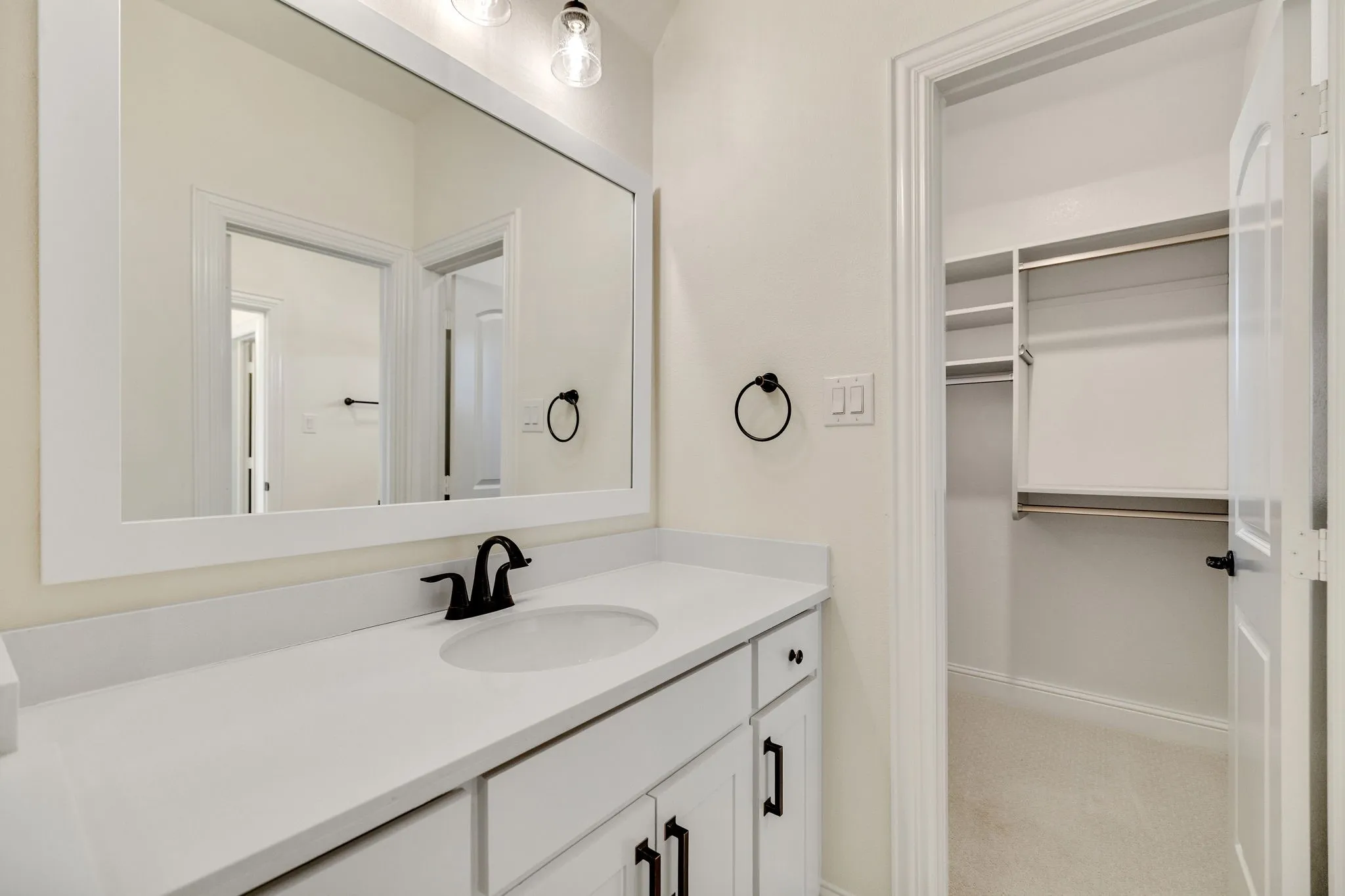 White vanity with integrated sink, matte black faucet, and framed mirror