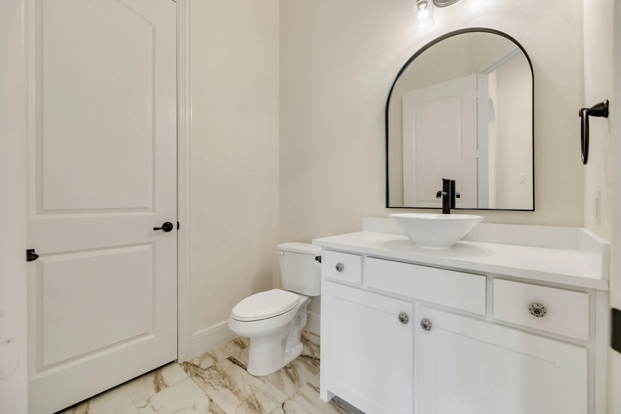 White vanity with a vessel sink, quartz countertop, and black wall-mounted faucet